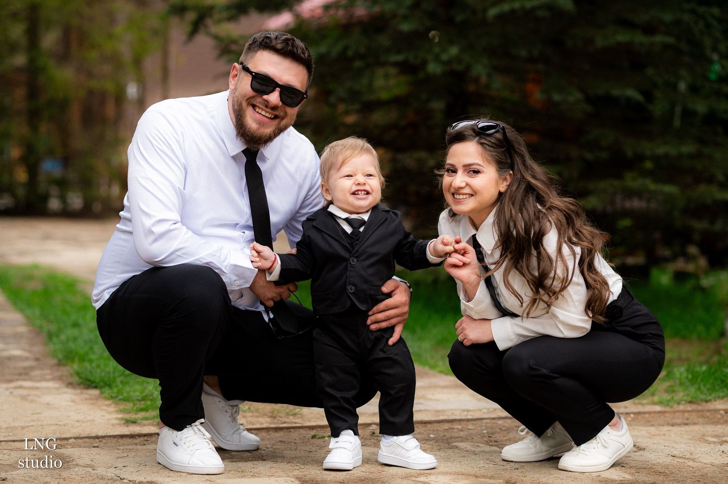 Family in coordinated outfits crouching together for a casual outdoor portrait.