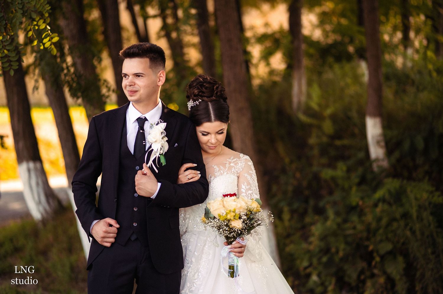 Newlyweds share a joyful moment while walking through a wooded setting.
