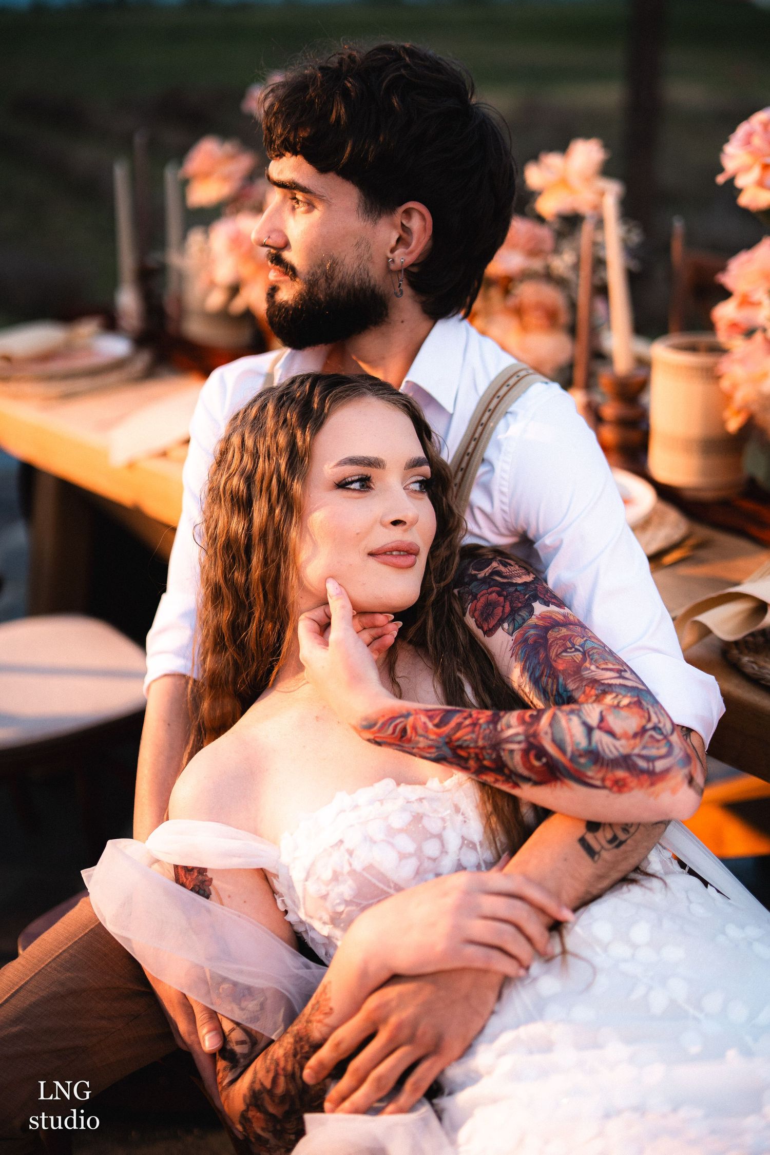 Romantic wedding couple sharing tender moments during sunset outdoor reception with soft lighting and warm tones.