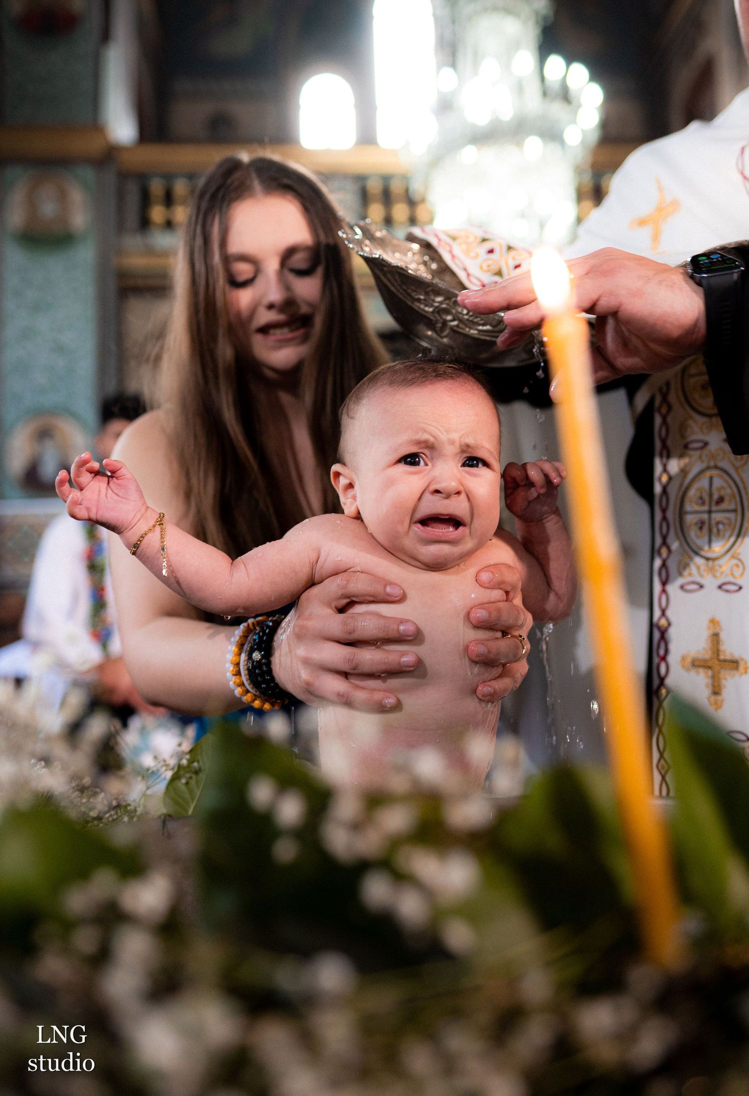 Orthodox baptism ceremony with lit candles and religious symbols.