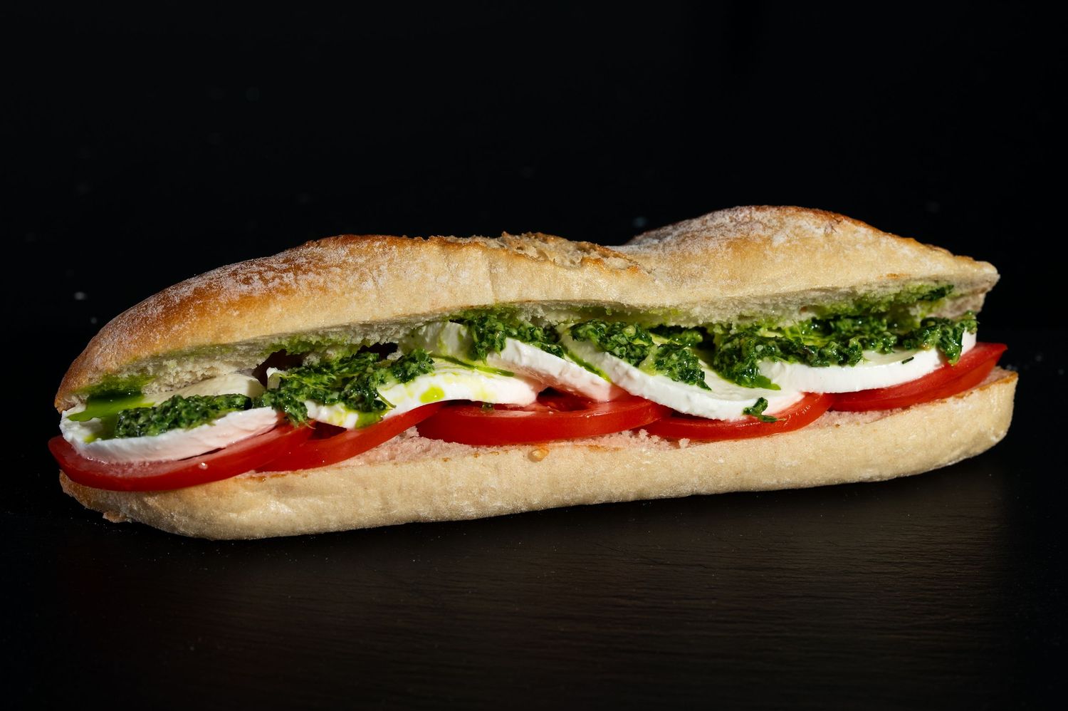 Italian submarine sandwich with mozzarella, tomatoes and leafy greens on artisan bread.