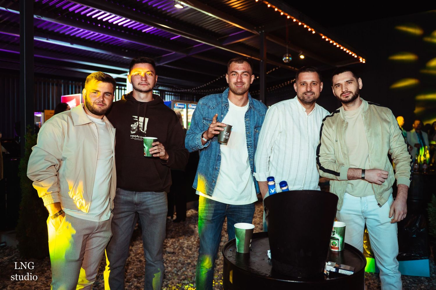 Group gathering at casual nighttime event with string lights overhead.