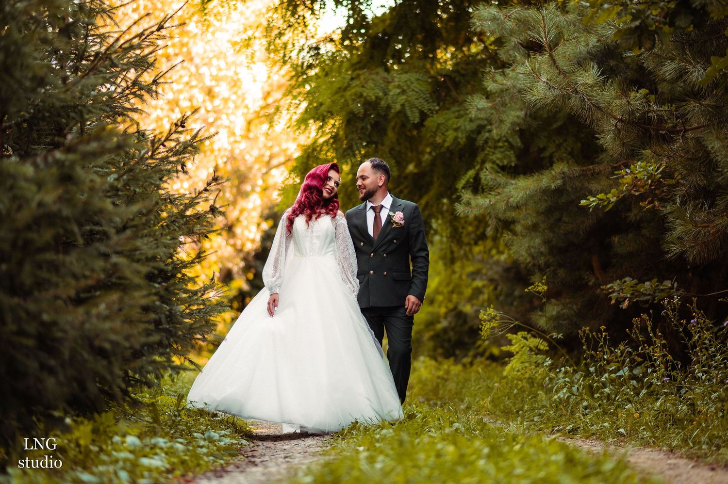 Romantic wedding portraits captured in golden sunset light among trees and greenery.