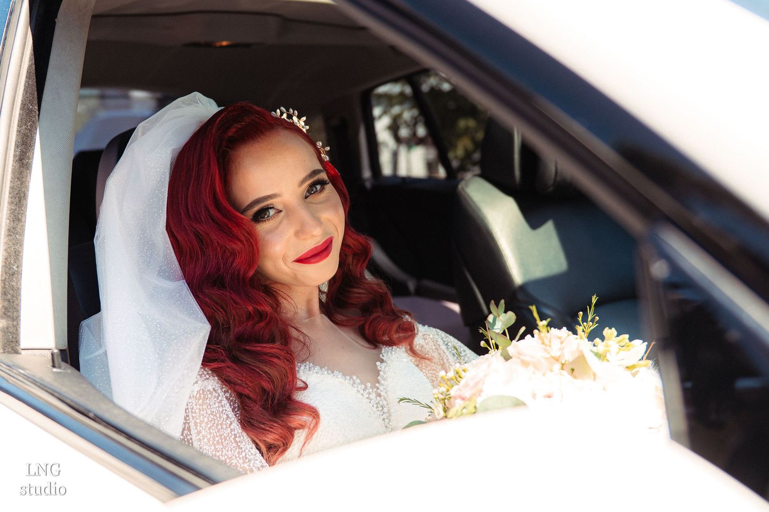 Wedding couple seated in car with natural sunlight streaming through window.