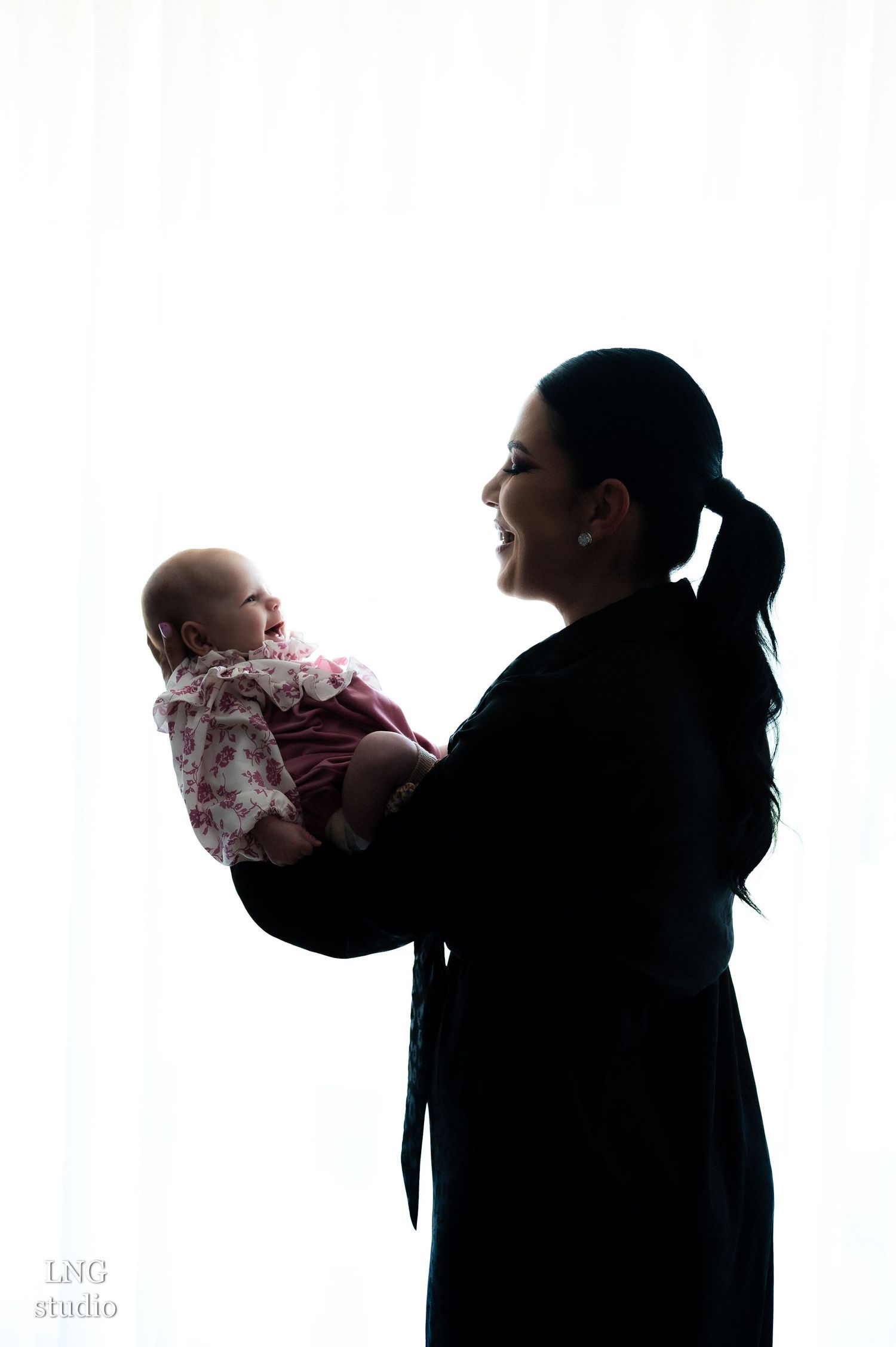 Silhouette portrait of a caregiver holding a baby against a white background.