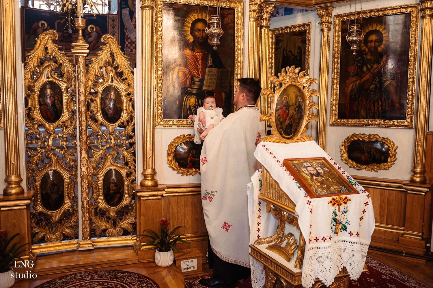 A religious ceremony being performed in front of an ornate golden Orthodox church altar.