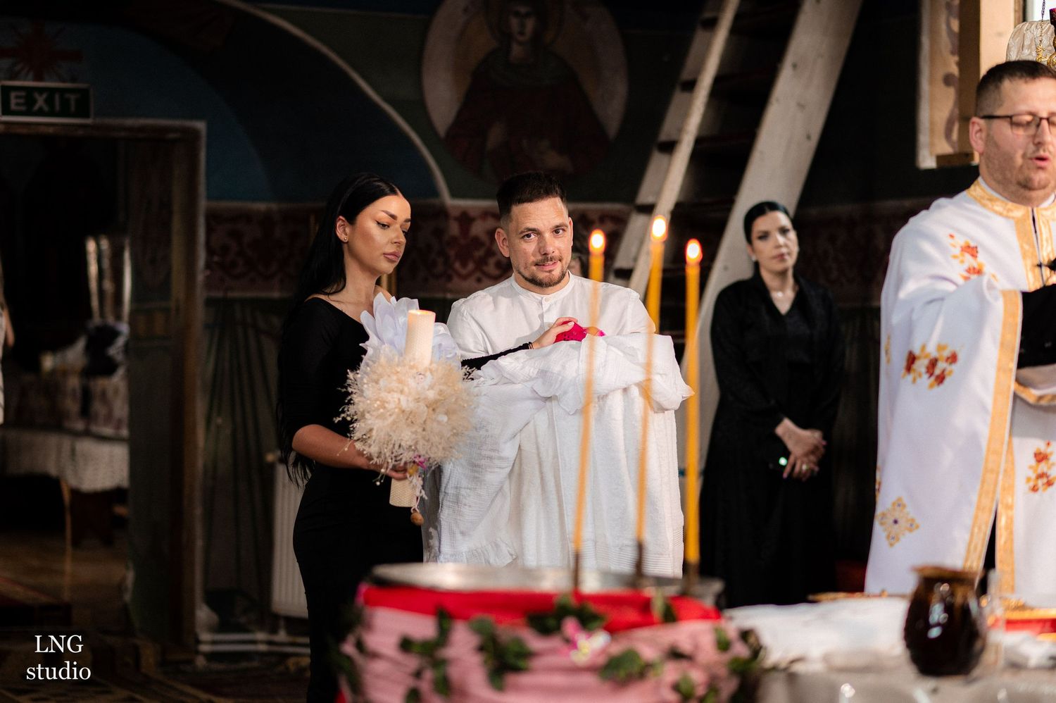Traditional Orthodox baptism service with clergy and family gathered.
