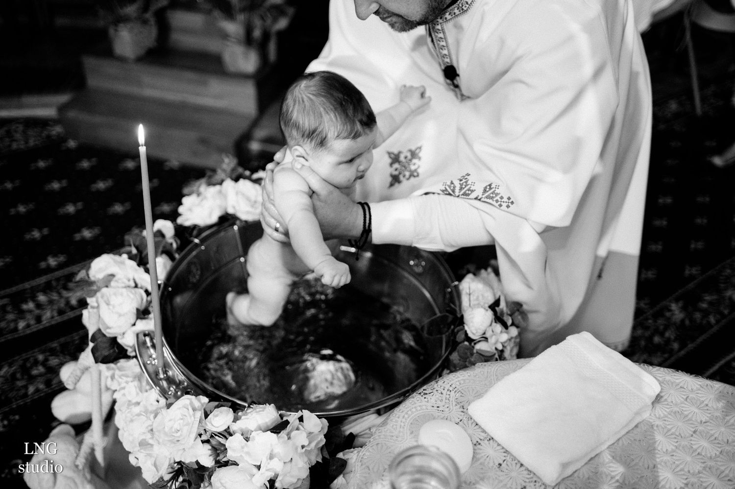 Black and white photo of baptism ceremony with floral decorations.