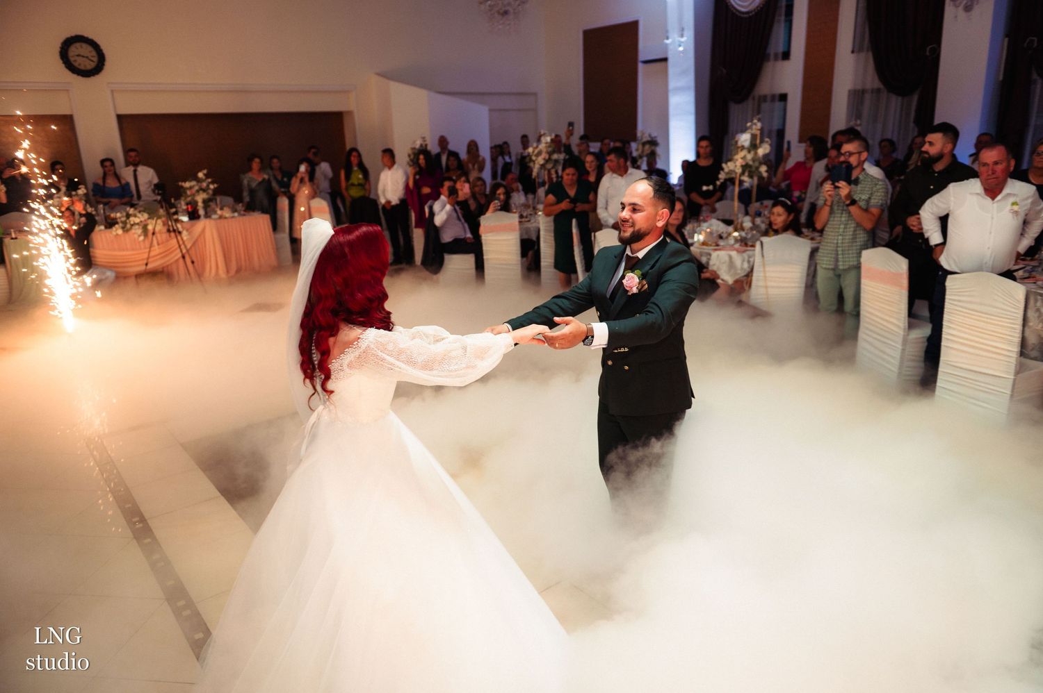 Couple dancing on misty white floor during their first dance at wedding reception.