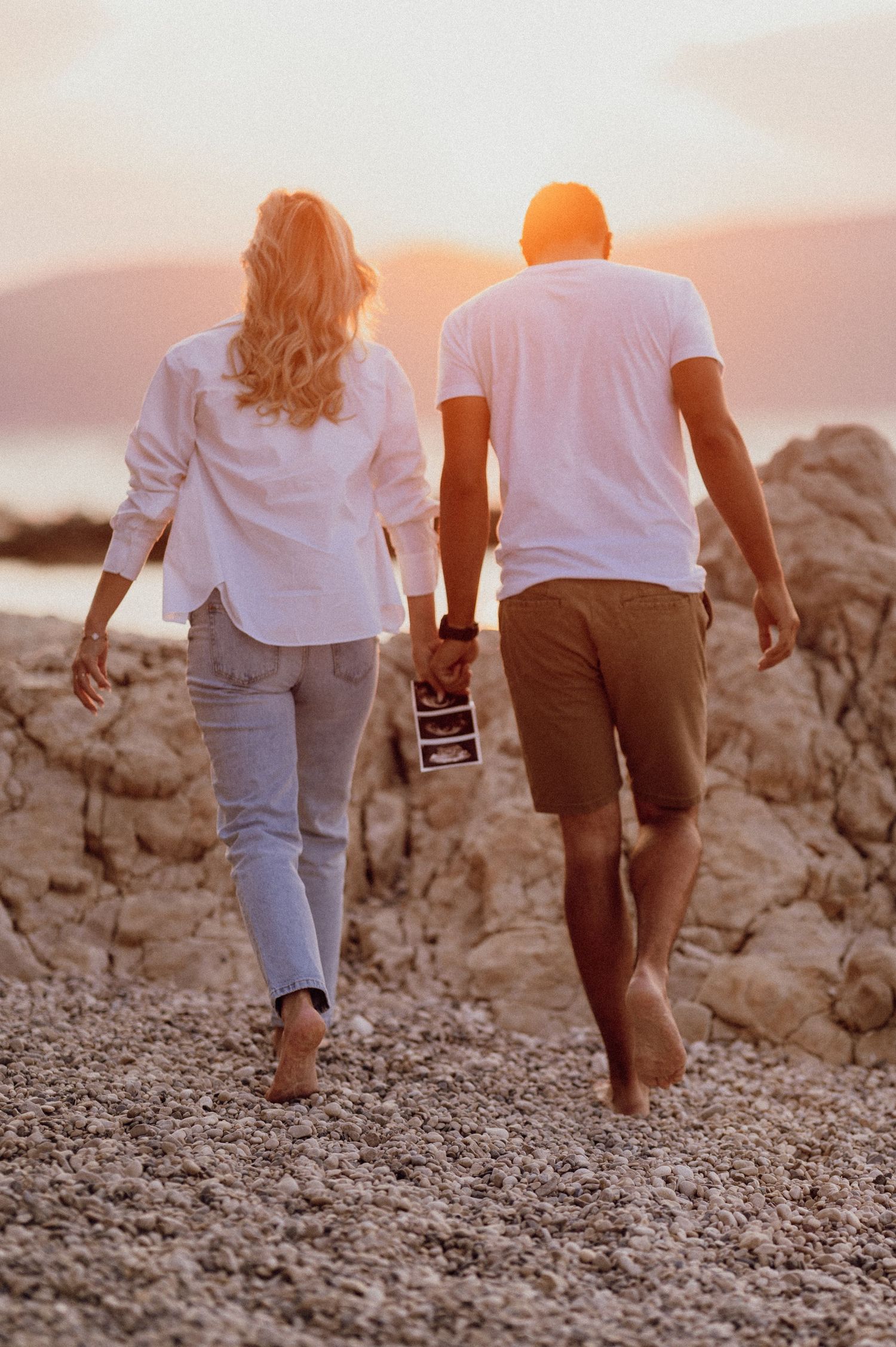 Expectant couple walking hand in hand on the beach at dawn, Istria