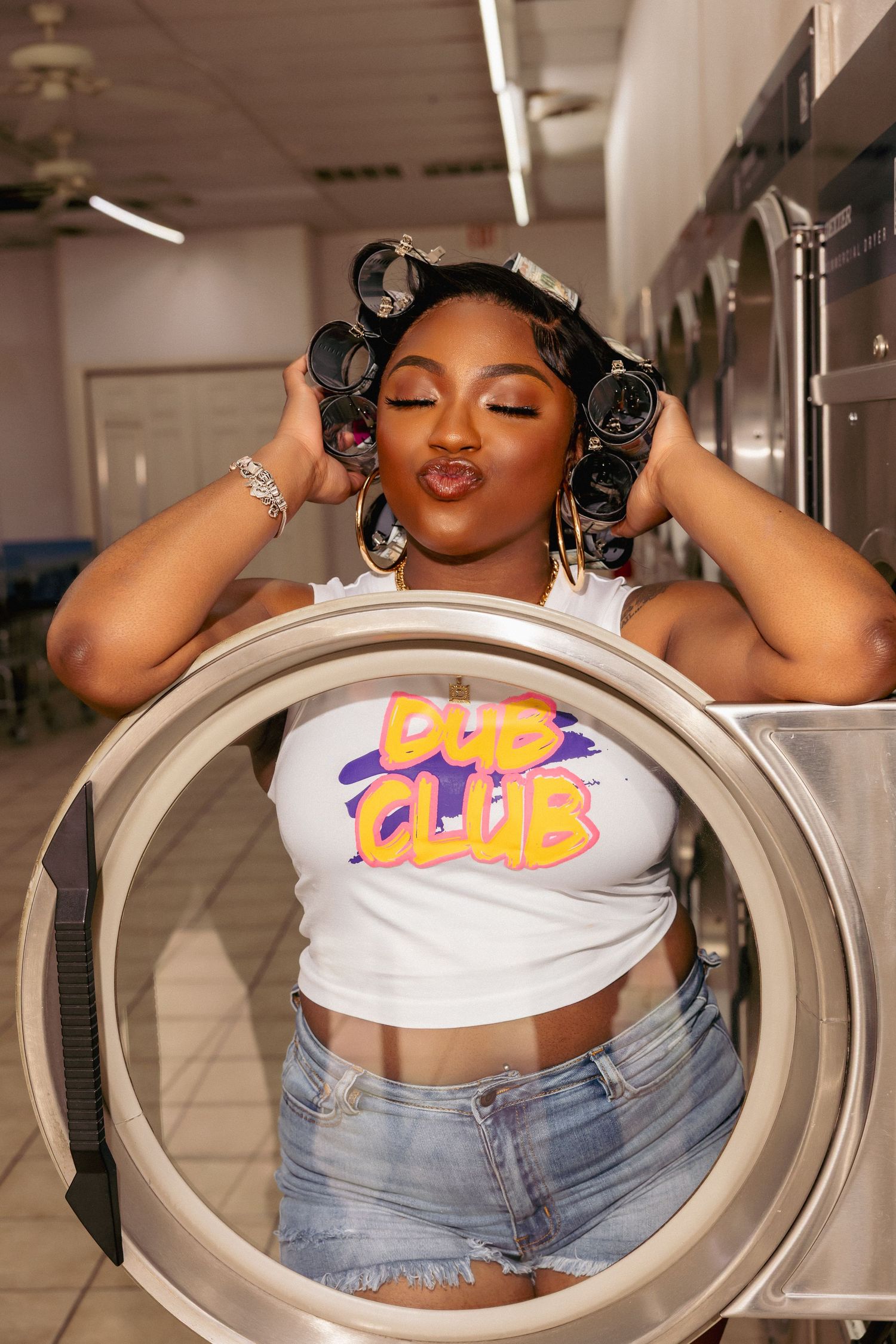 Candid laundromat photoshoot with casual crop top and hair rollers.