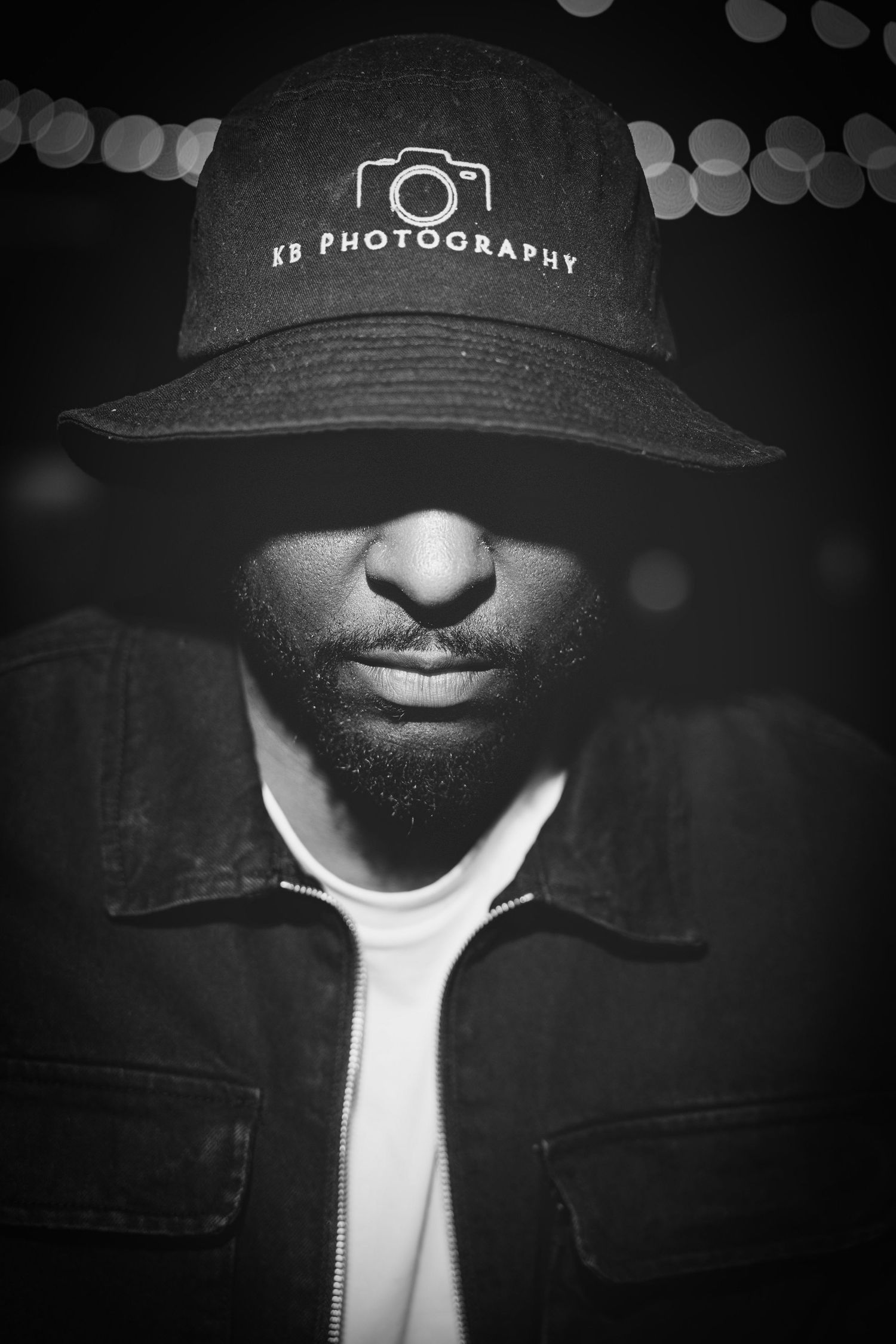 Moody black and white portrait series focusing on a baseball cap with photography branding.