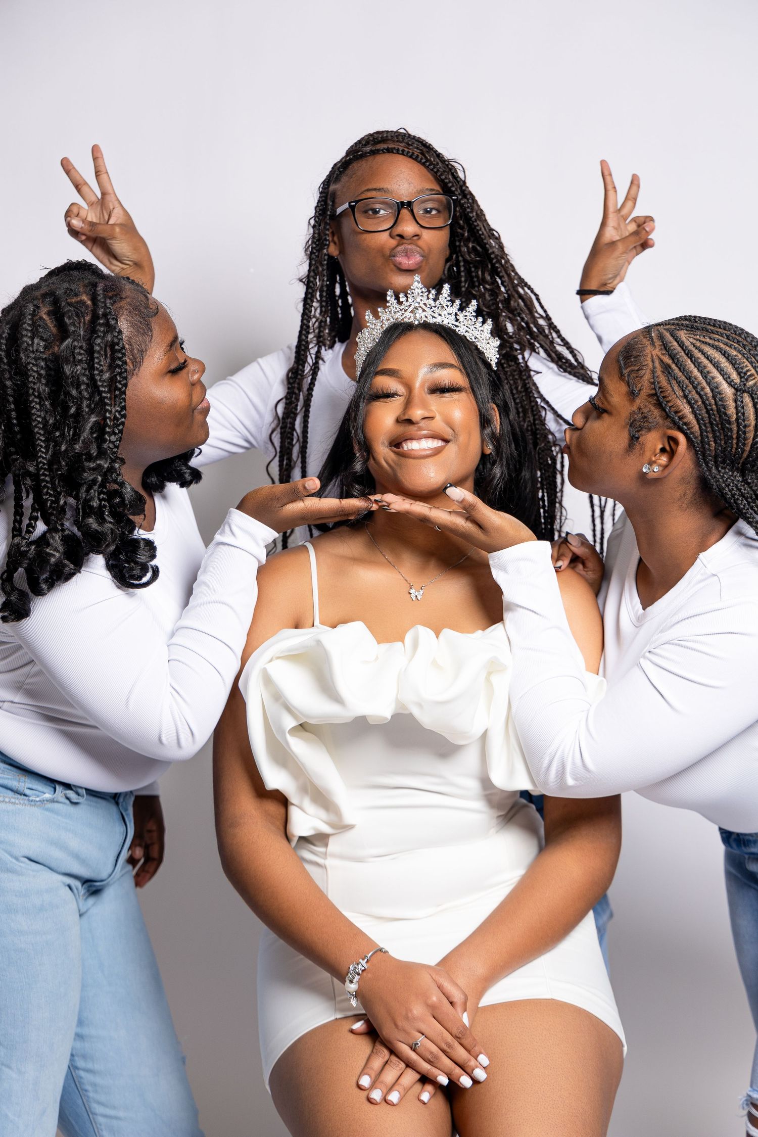 Group photoshoot with models in white outfits showing peace signs and joyful expressions.