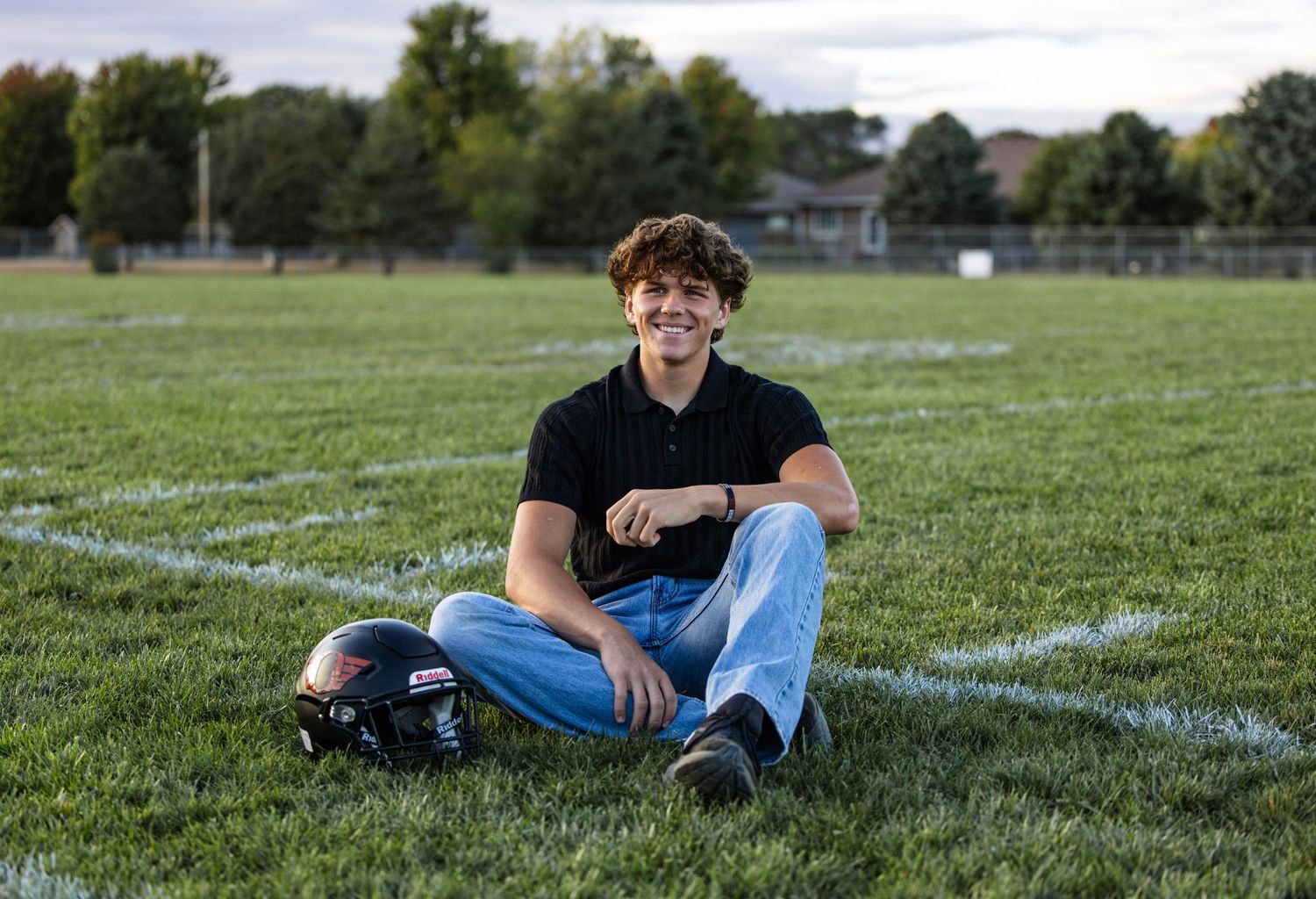 boy senior picture, on football field, sitting