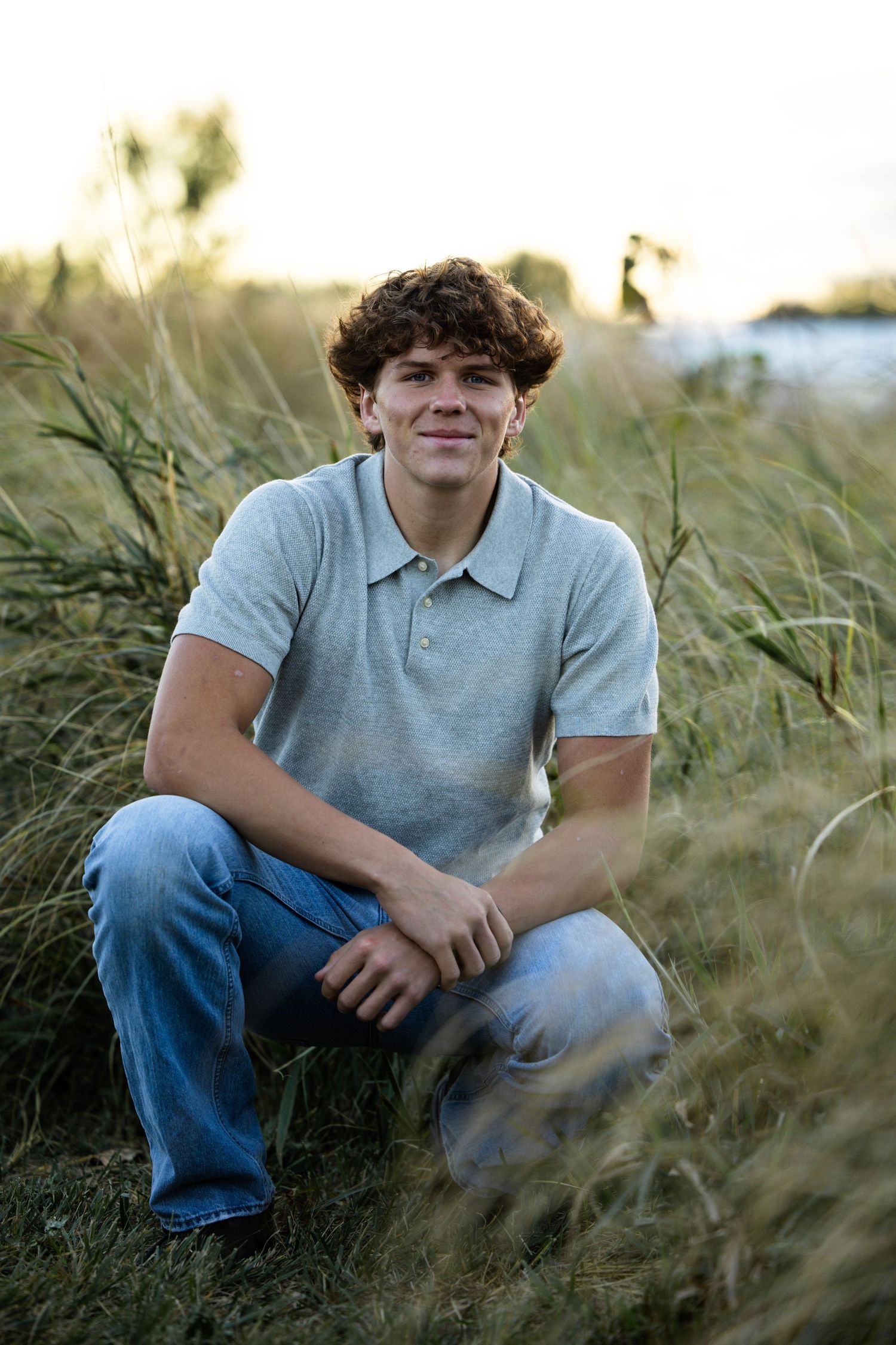 boy senior picture, sunset, squatting, close up