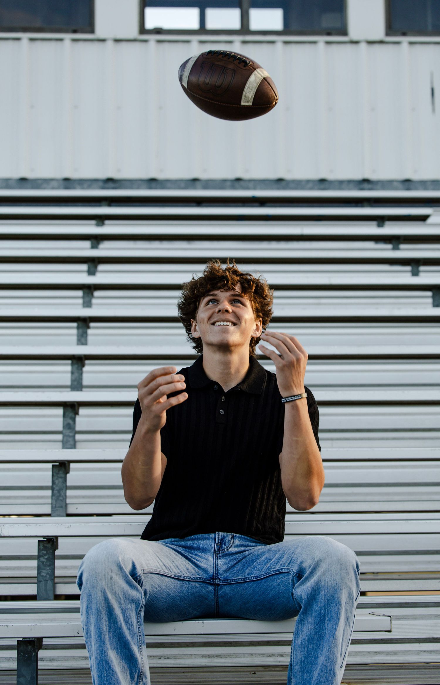 football player throwing ball in the air on the bleachers