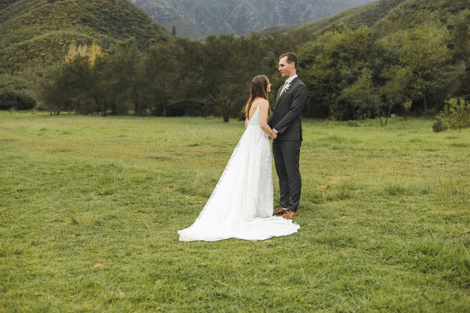 Couple shares romantic moments on a picturesque mountain trail with lush green scenery.