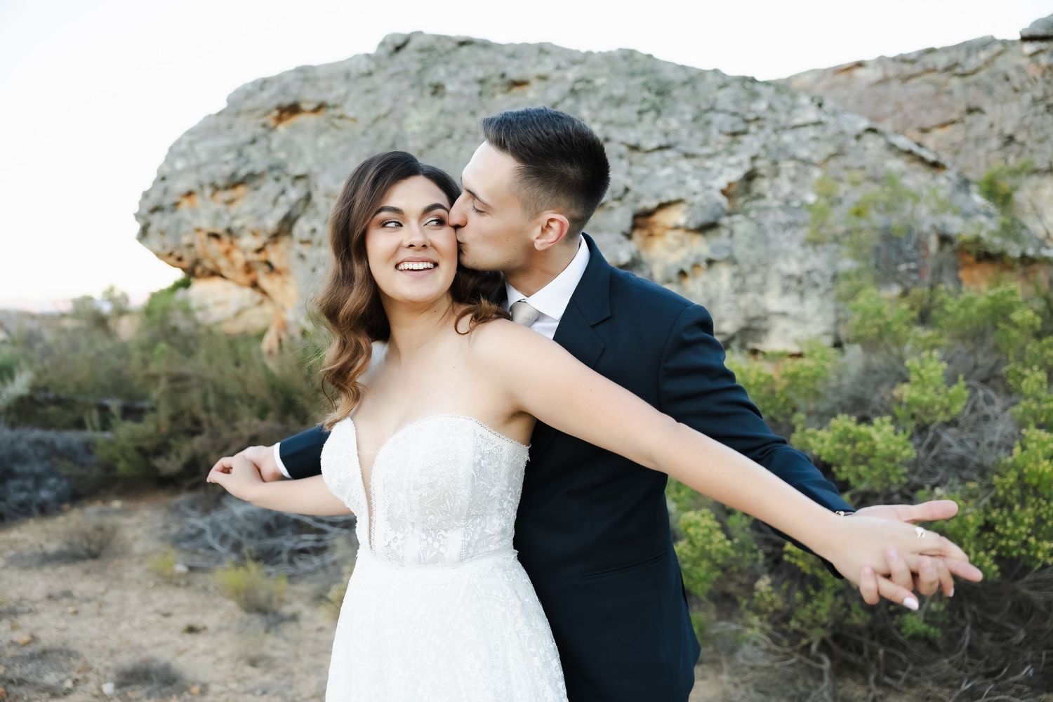 Joyful wedding portraits captured on scenic mountain overlook at sunset.
