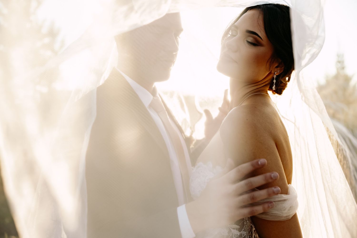 Soft dreamy lighting creates ethereal bridal portrait through flowing veil.