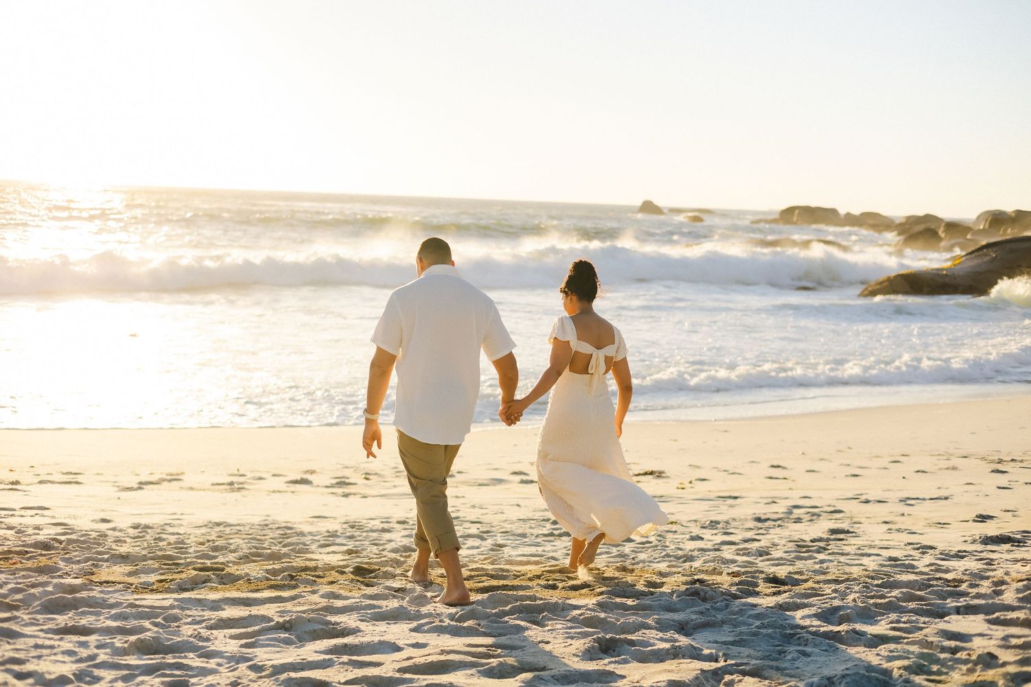A couple walking together on a sunny beach at sunset holding hands and enjoying the romantic seaside atmosphere.