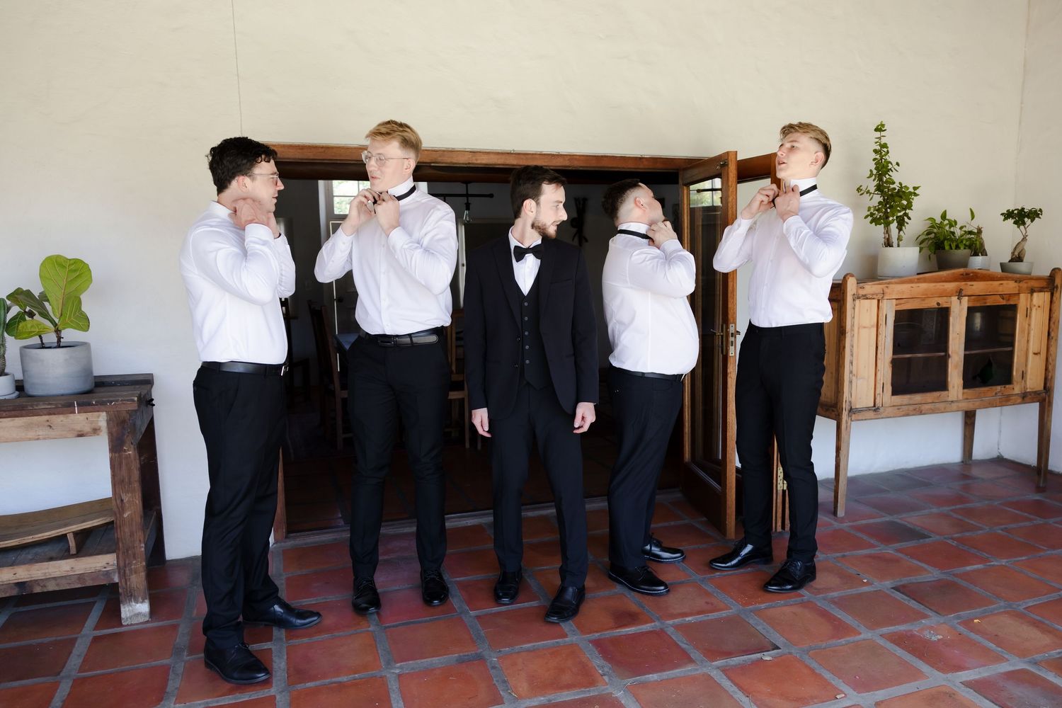 A group in formal white shirts and black pants standing together on terracotta tiles.