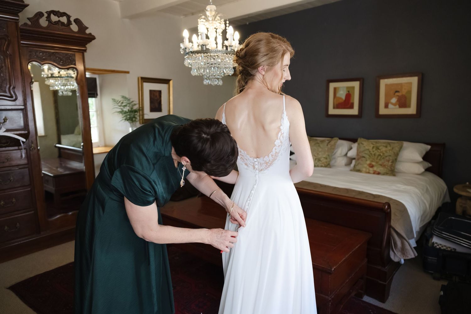 Elegant bridal preparation scene in a room with chandelier and dark accent wall.