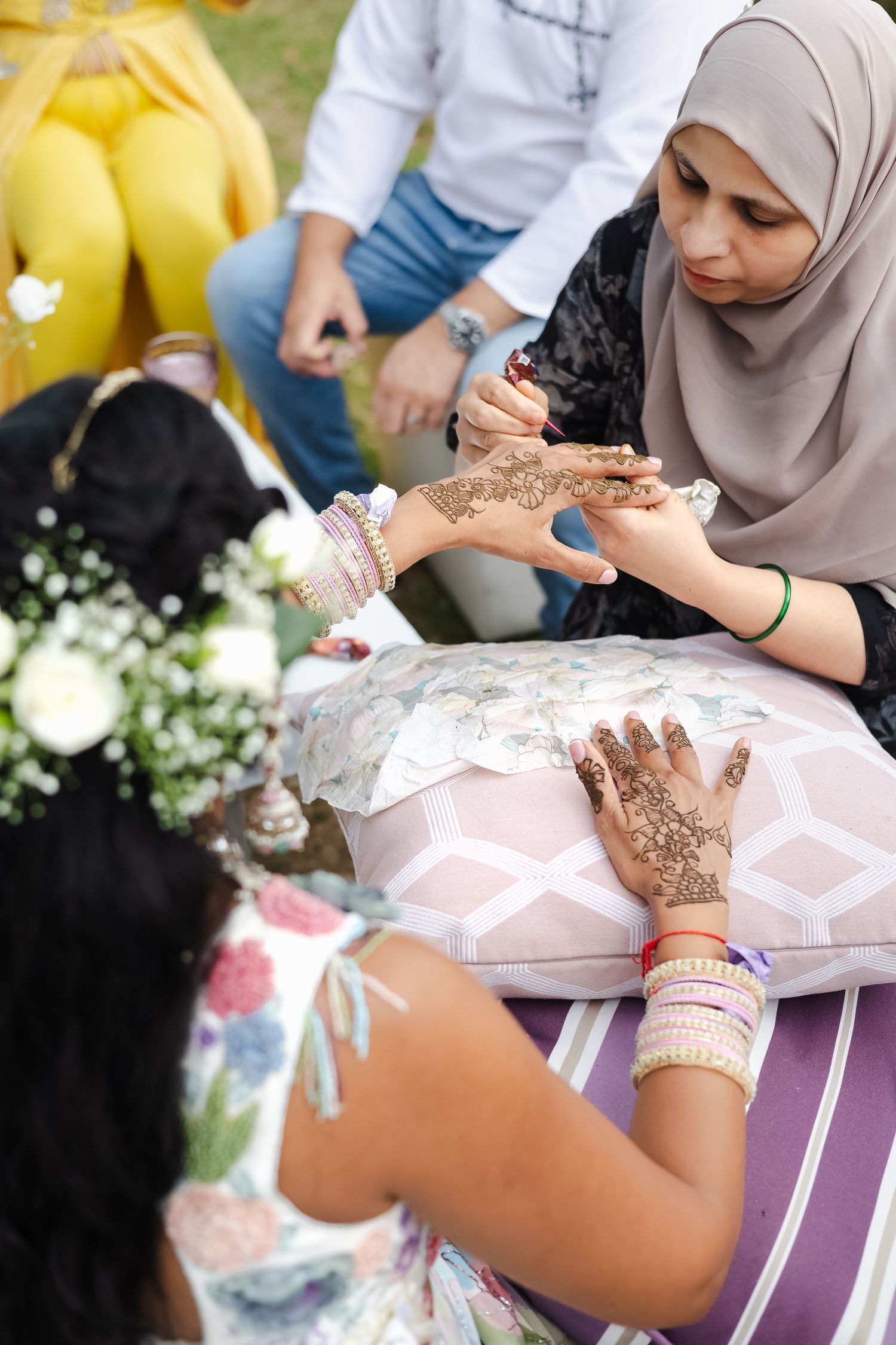 A close-up view of hands applying intricate henna designs during a traditional celebration.