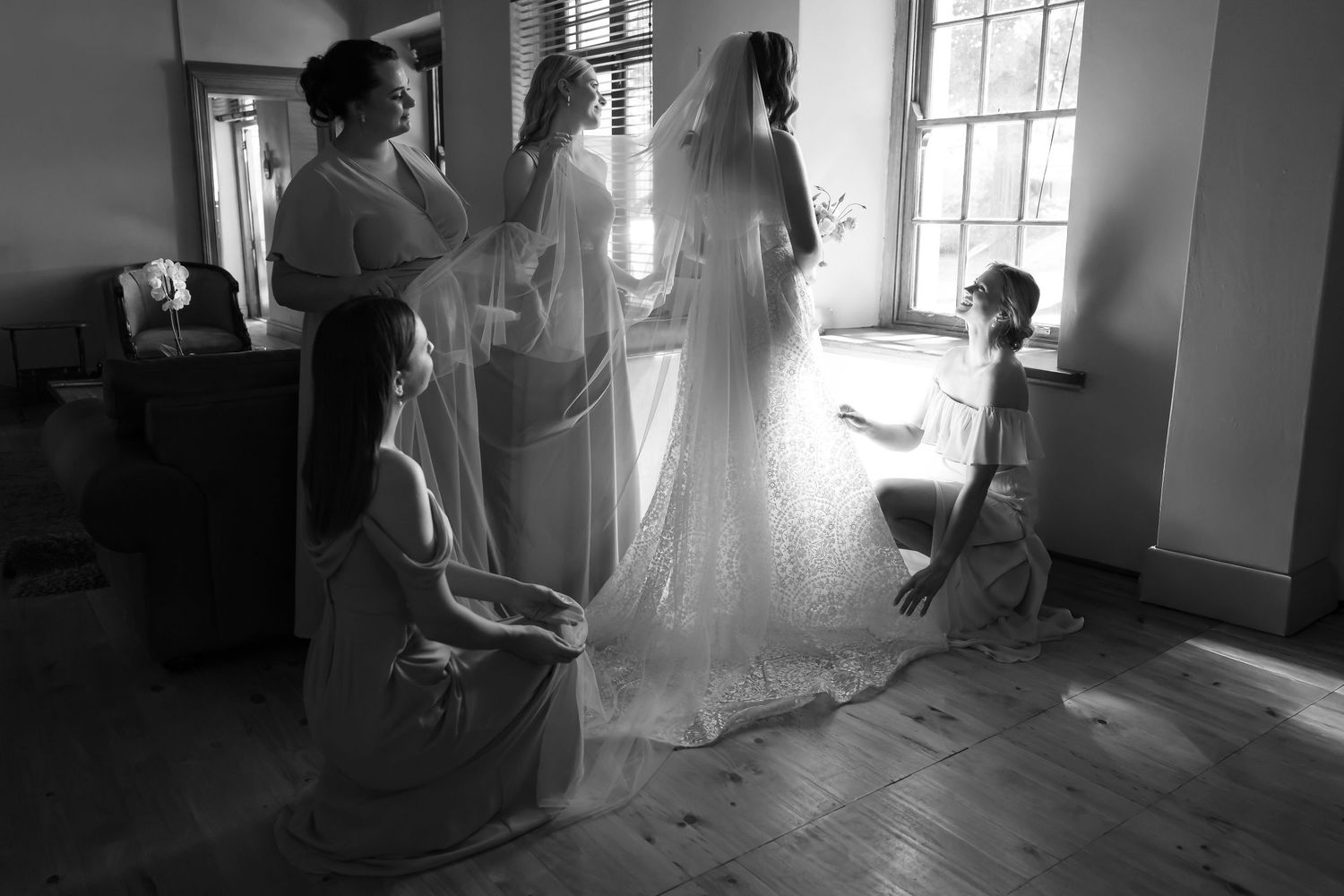 A series of black and white photos showing a person dancing with a flowing white fabric in a sunlit room.