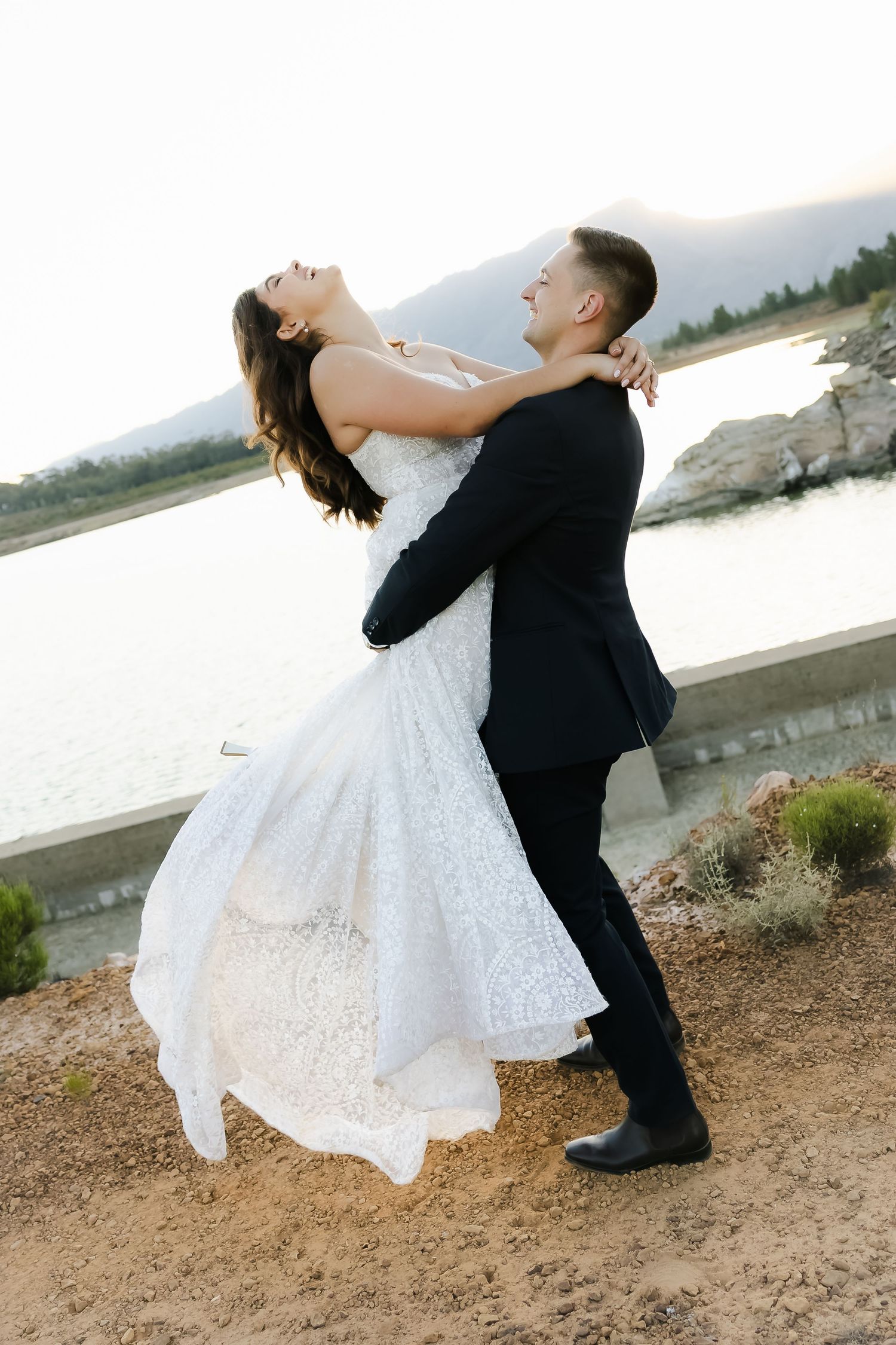 Romantic dance sequence showing a couple in wedding attire twirling by the waterfront at sunset.