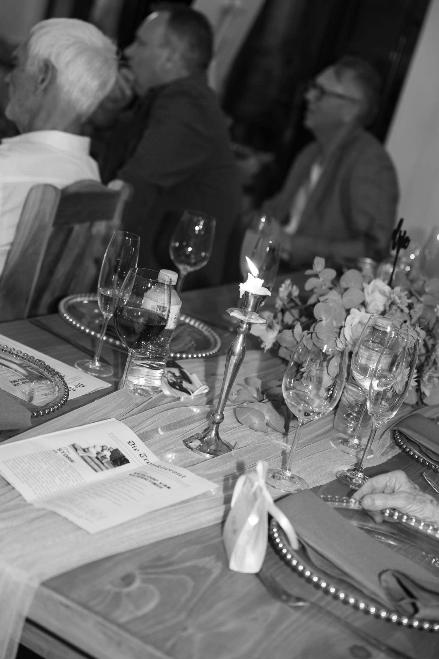Elegant table setting with wine glasses, candles and floral arrangements at a formal event.