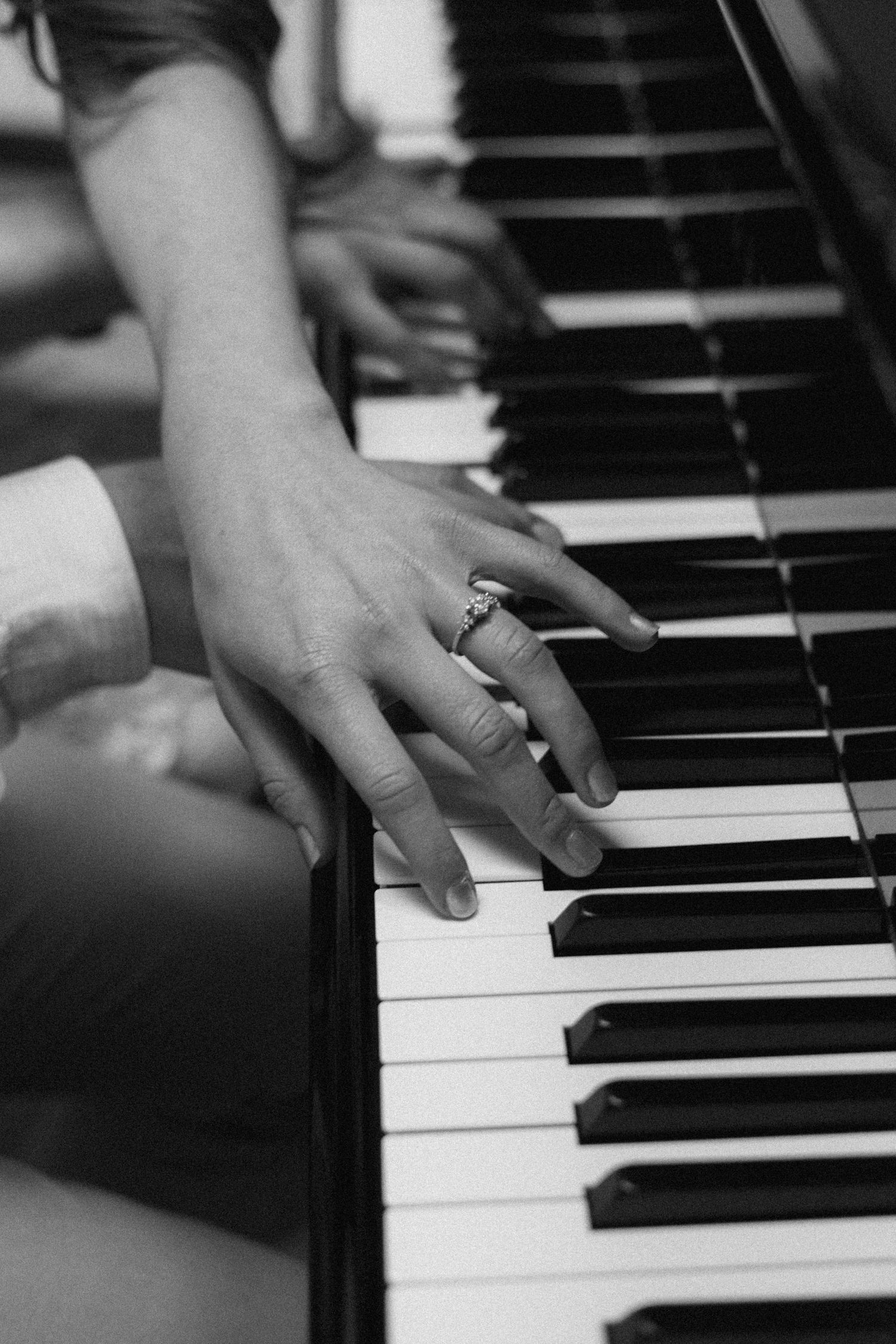 Black and white close-up sequence of hands playing piano keys in progression.