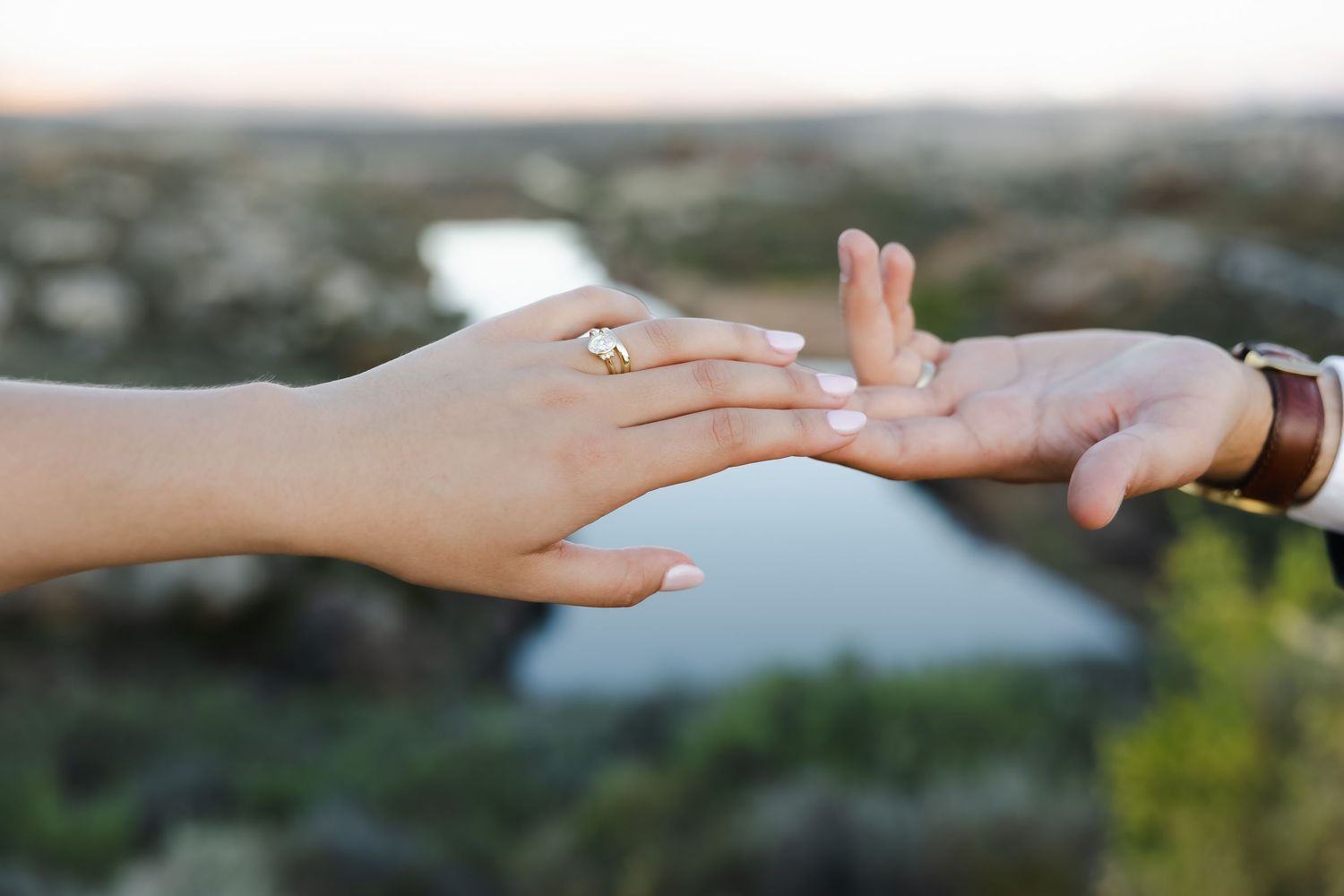 Close-up of hands with wedding rings touching in soft natural light.