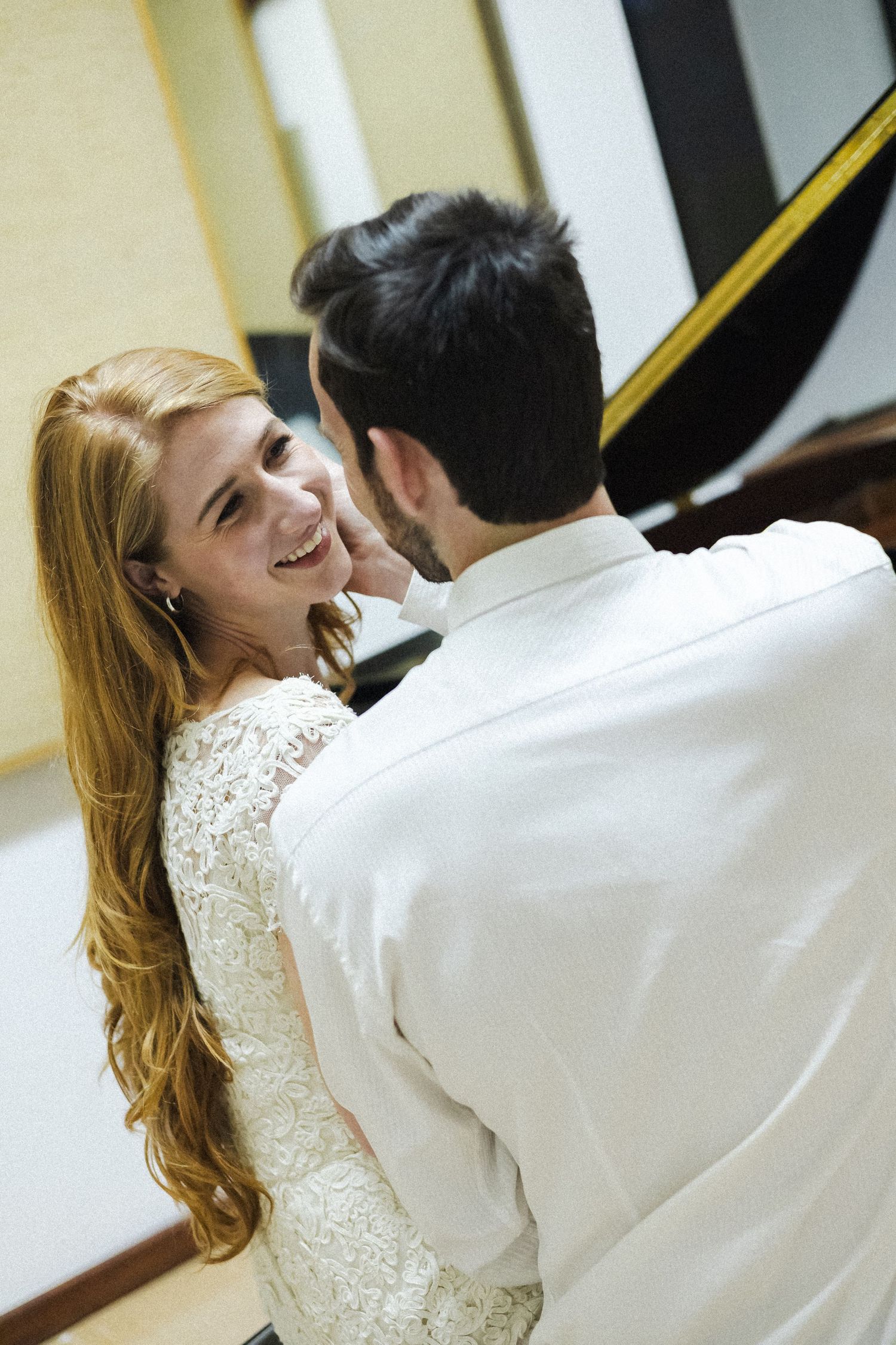A couple in wedding attire share a joyful moment while dancing, with the bride wearing a lace dress and having long blonde hair.