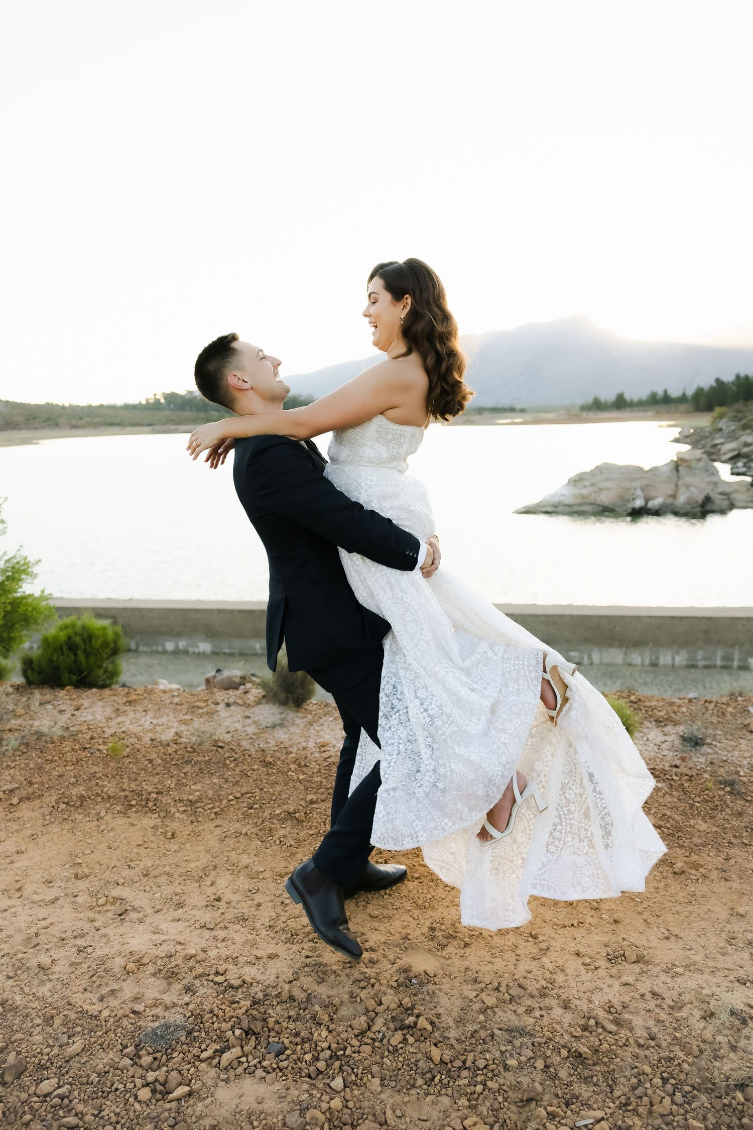 Playful wedding photography sequence showing a dip pose near a lakeside landscape.