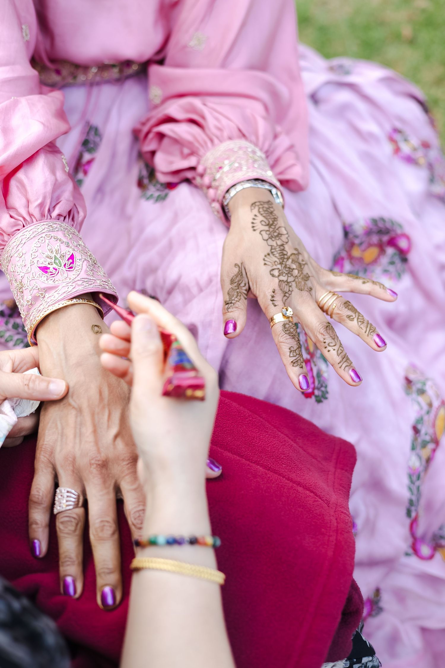 Close-up sequence showing hands applying intricate henna designs with glitter details during a traditional celebration.
