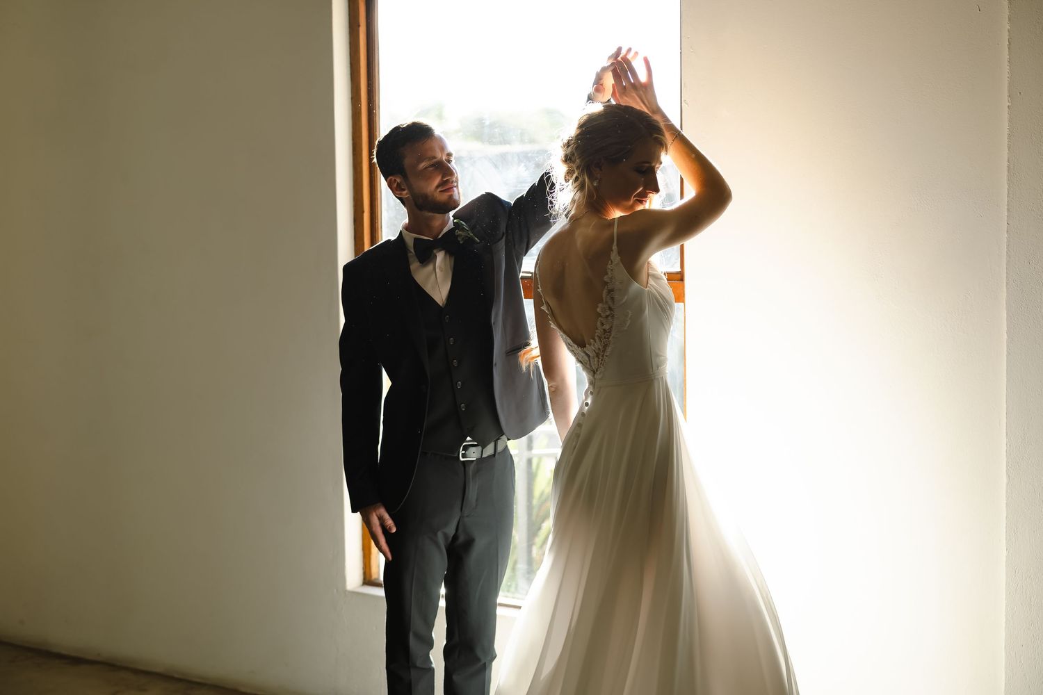 Bride and groom share an intimate moment in a softly lit hallway during their wedding celebration.