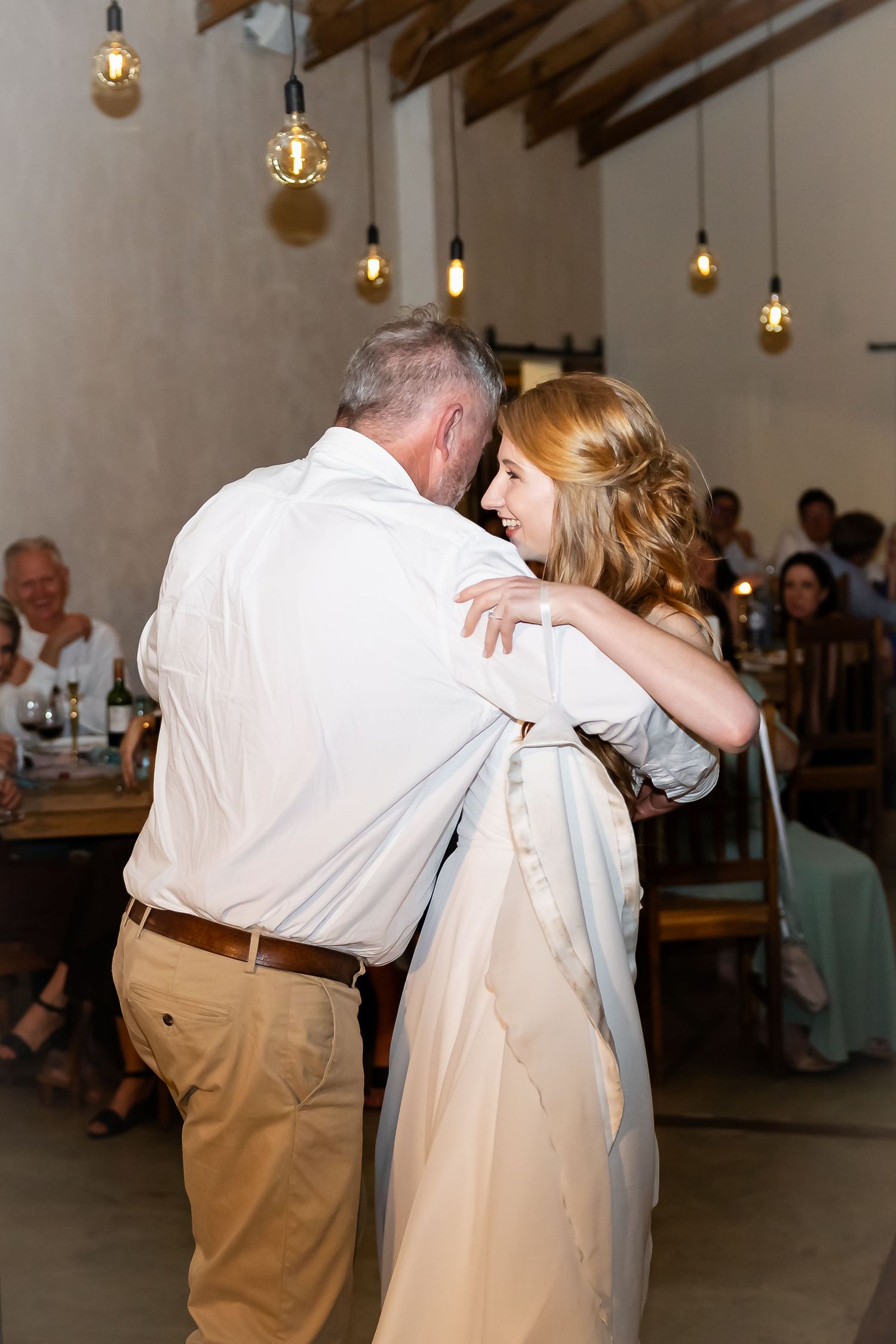 Couple sharing an intimate dance moment at a wedding reception with hanging lights.