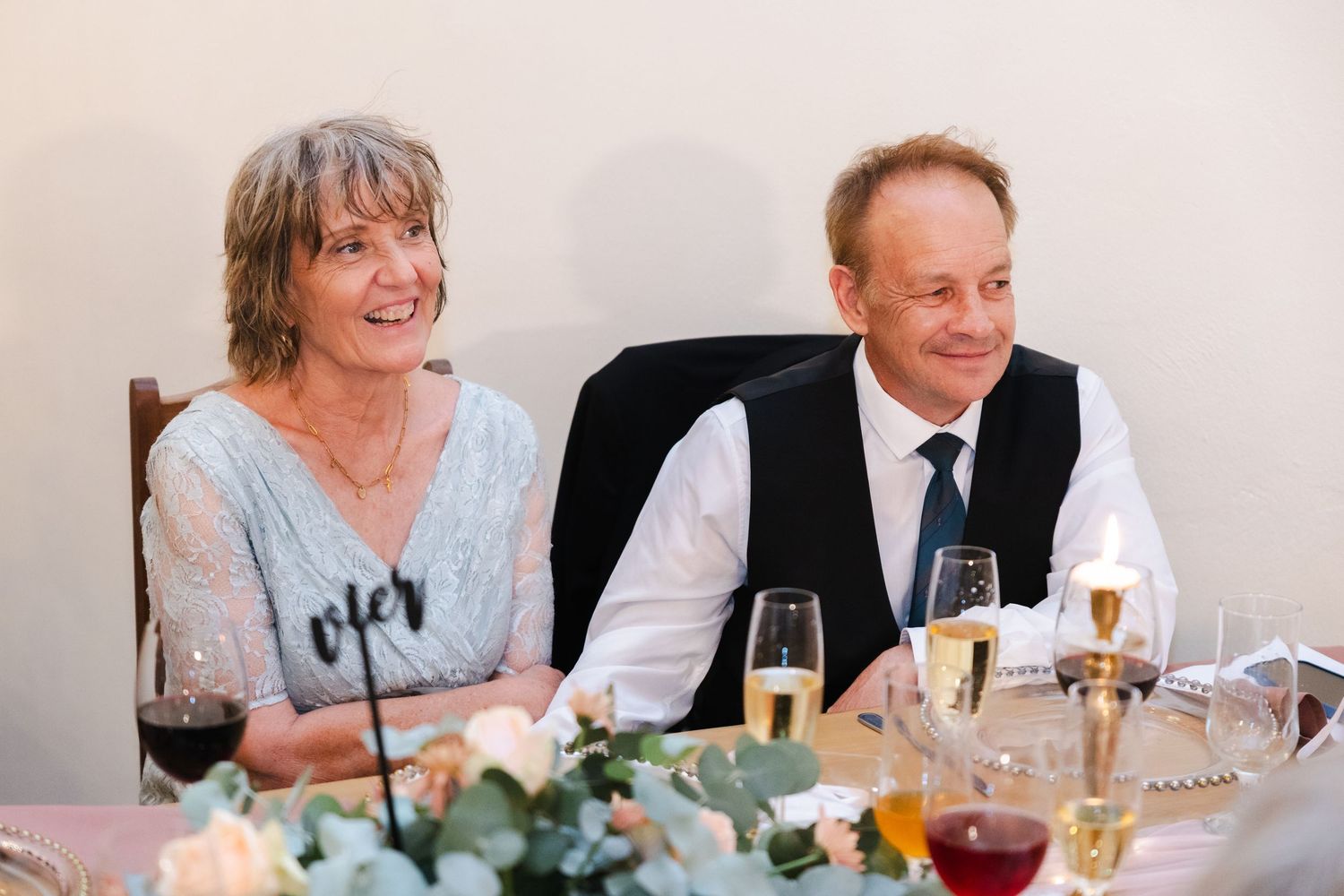 People enjoying a celebratory meal with drinks and laughter at an elegant dining table.