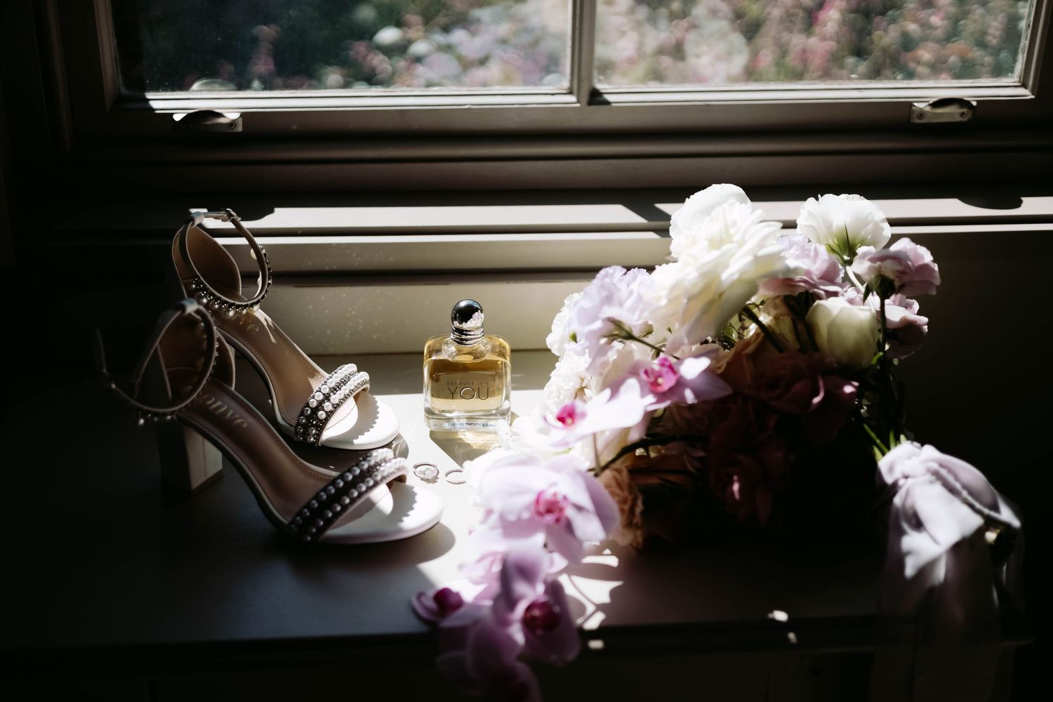 Pink orchids arranged by a window create a moody, artistic composition.