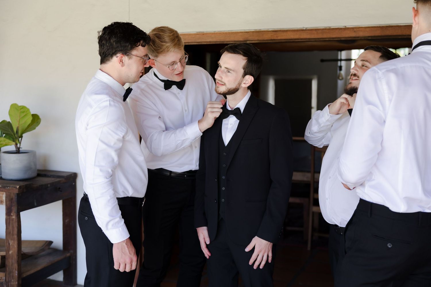 A group in formal attire sharing a lighthearted moment while getting ready for an event.