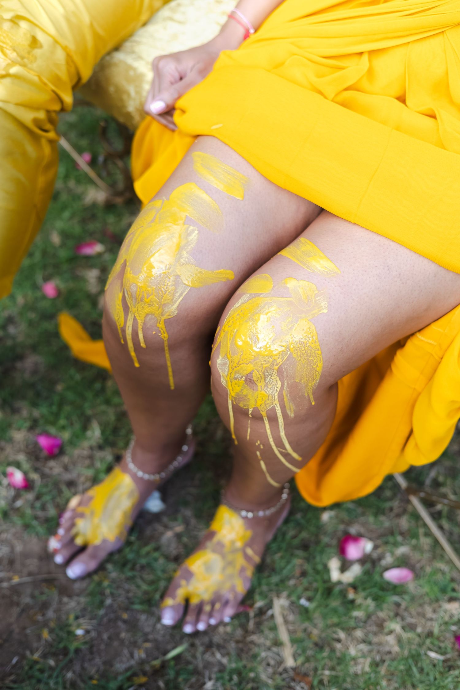 Yellow turmeric powder being applied to feet during a traditional Indian pre-wedding ceremony.