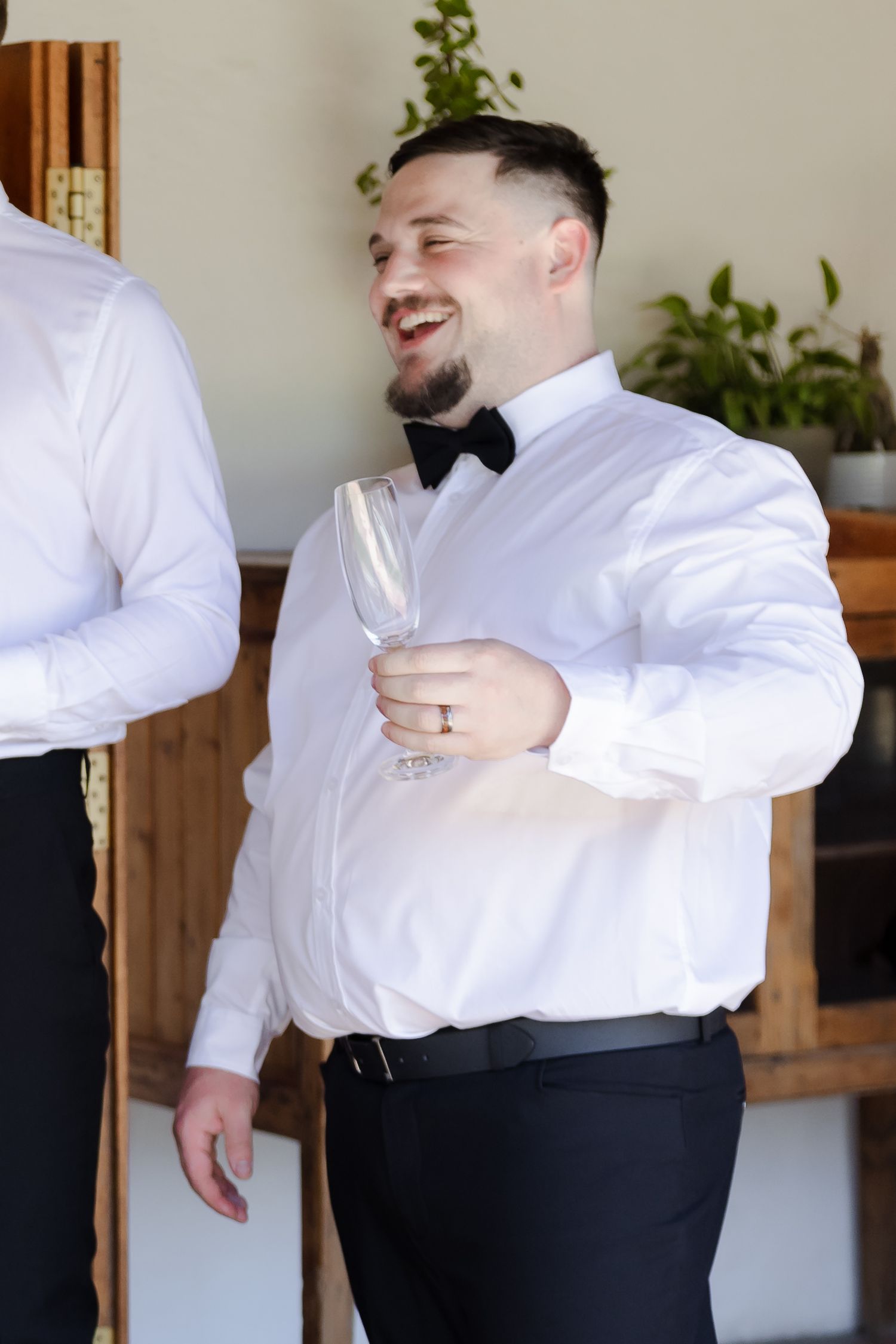 A person in formal attire laughs while holding a champagne glass during a celebration.