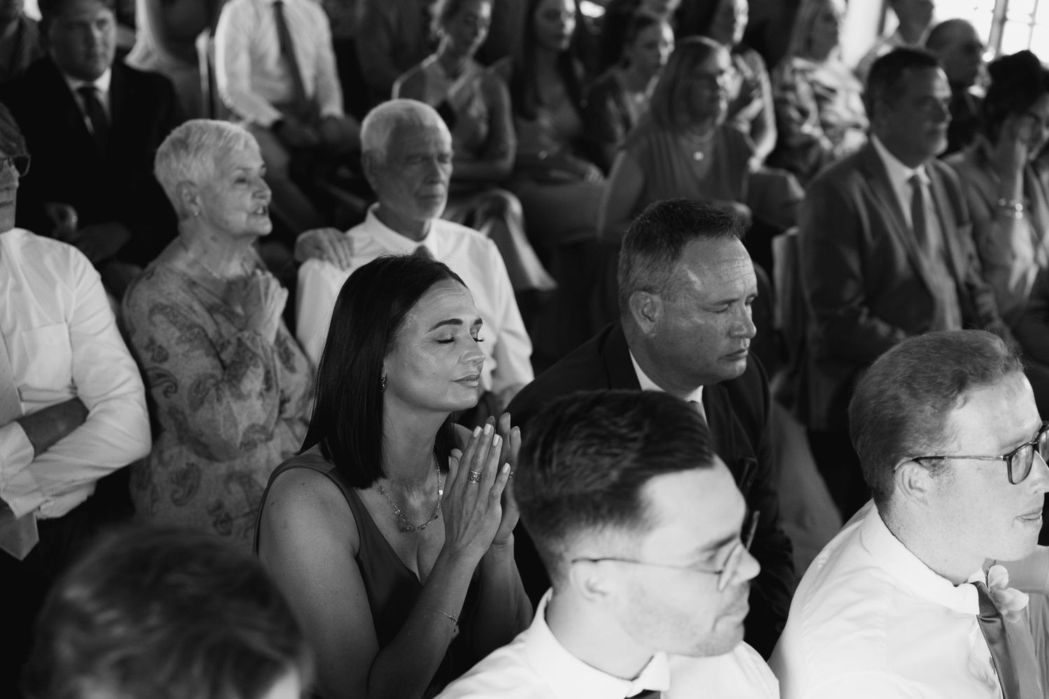 Wedding guests watching ceremony with emotional expressions in black and white photography.
