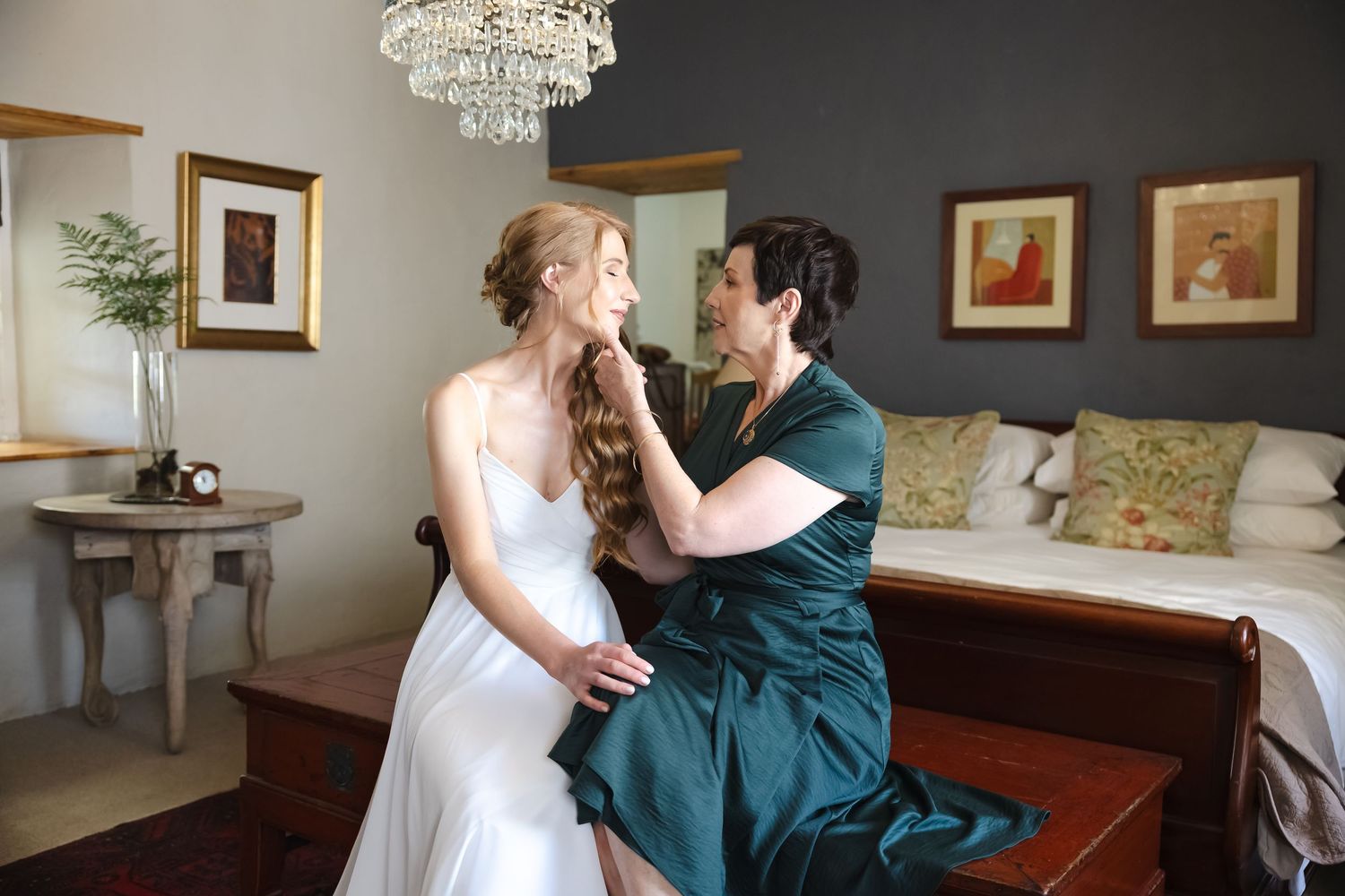 Intimate moment captured in an elegant room with crystal chandelier and dark walls.