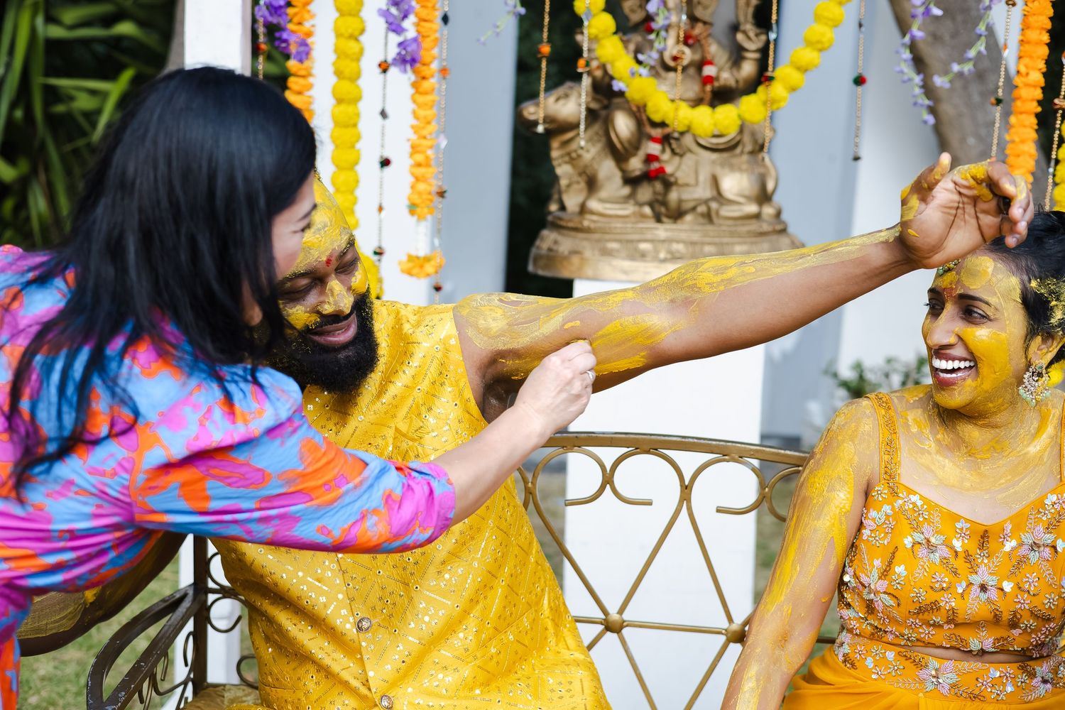 Colorful turmeric powder being thrown during Haldi ceremony at traditional Indian wedding celebration.