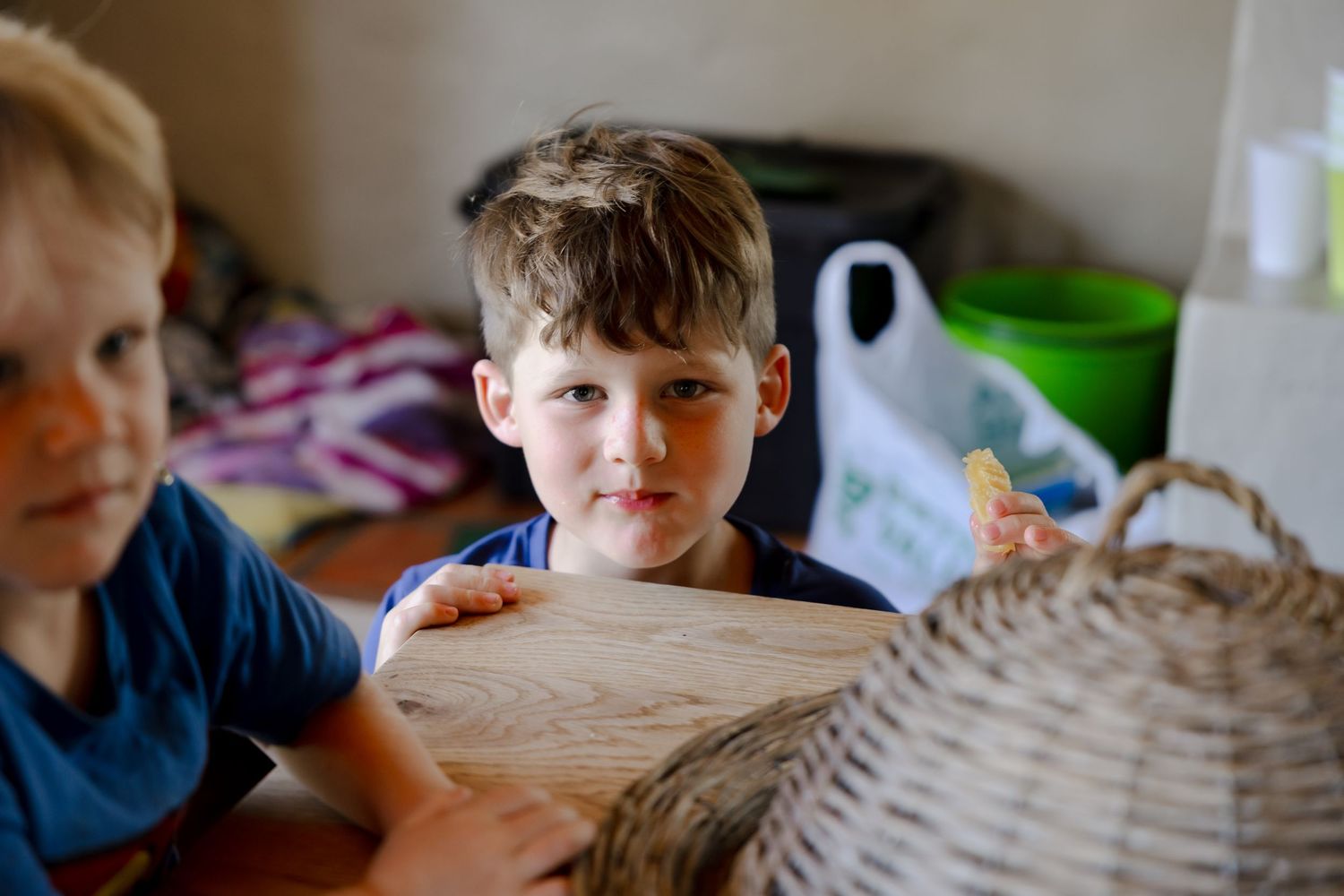 Children looking at a large woven basket or object in an indoor setting.