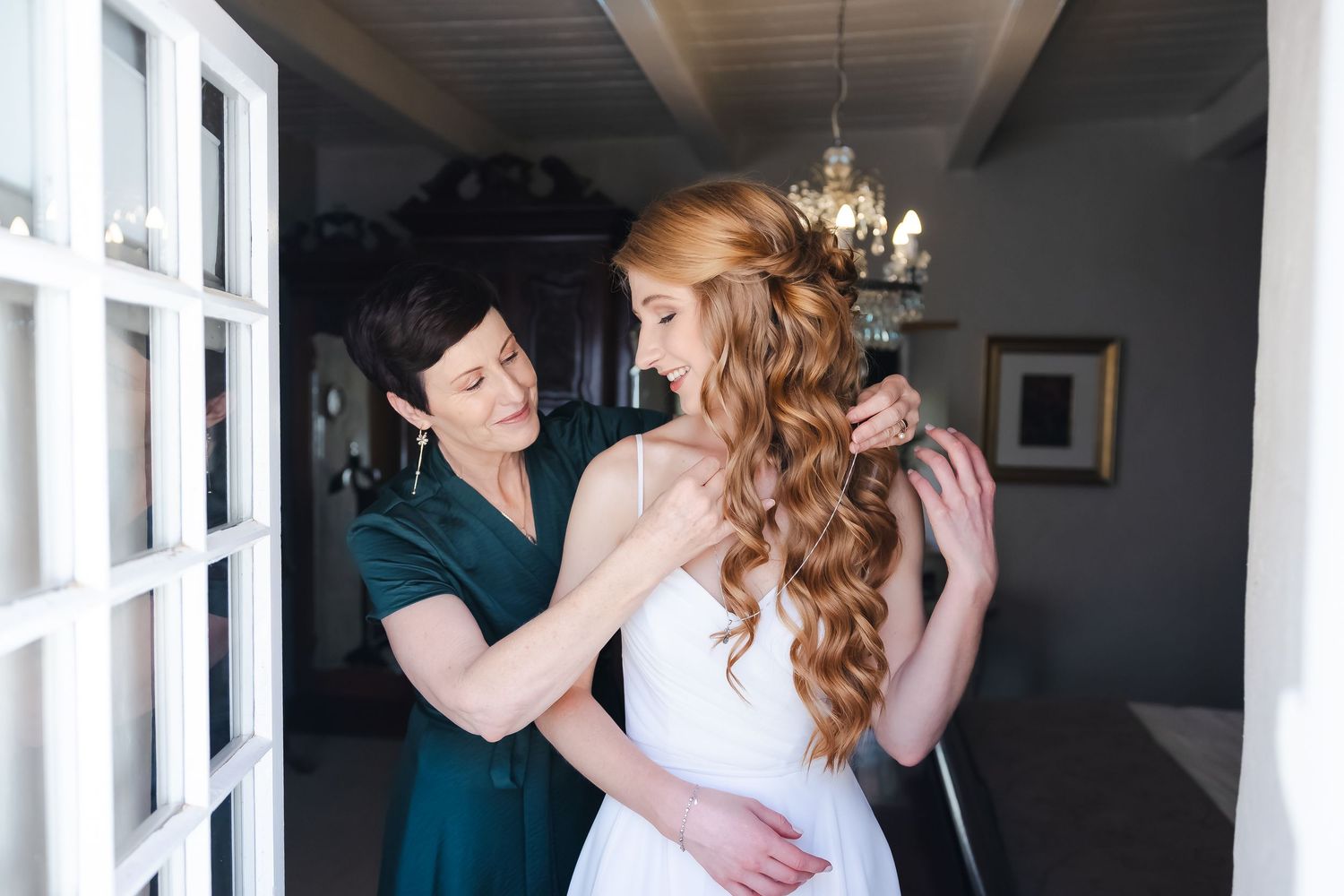 Natural light streams through white windows during a tender wedding moment.