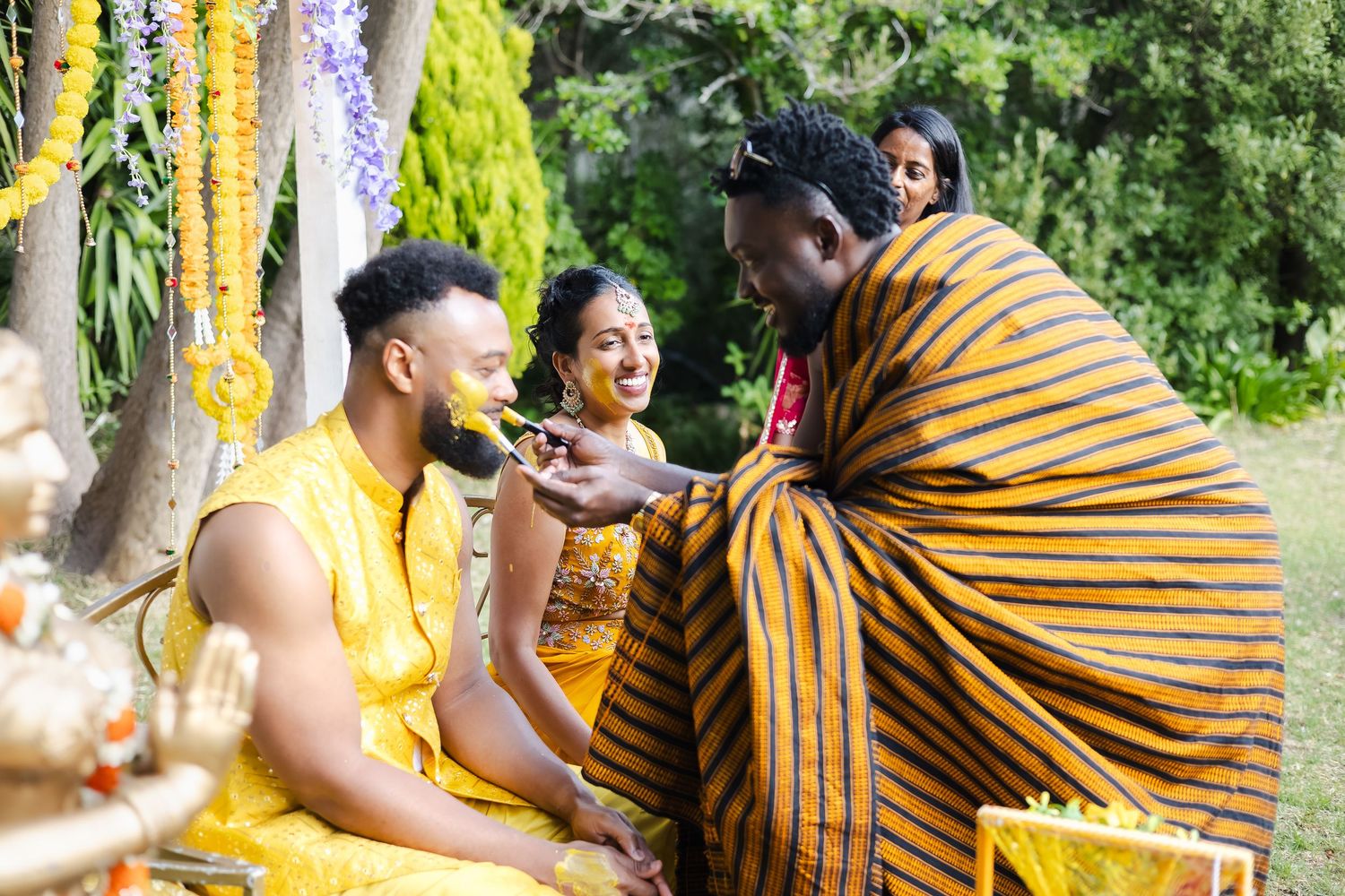 People in traditional yellow and brown striped clothing gather outdoors for a cultural celebration.