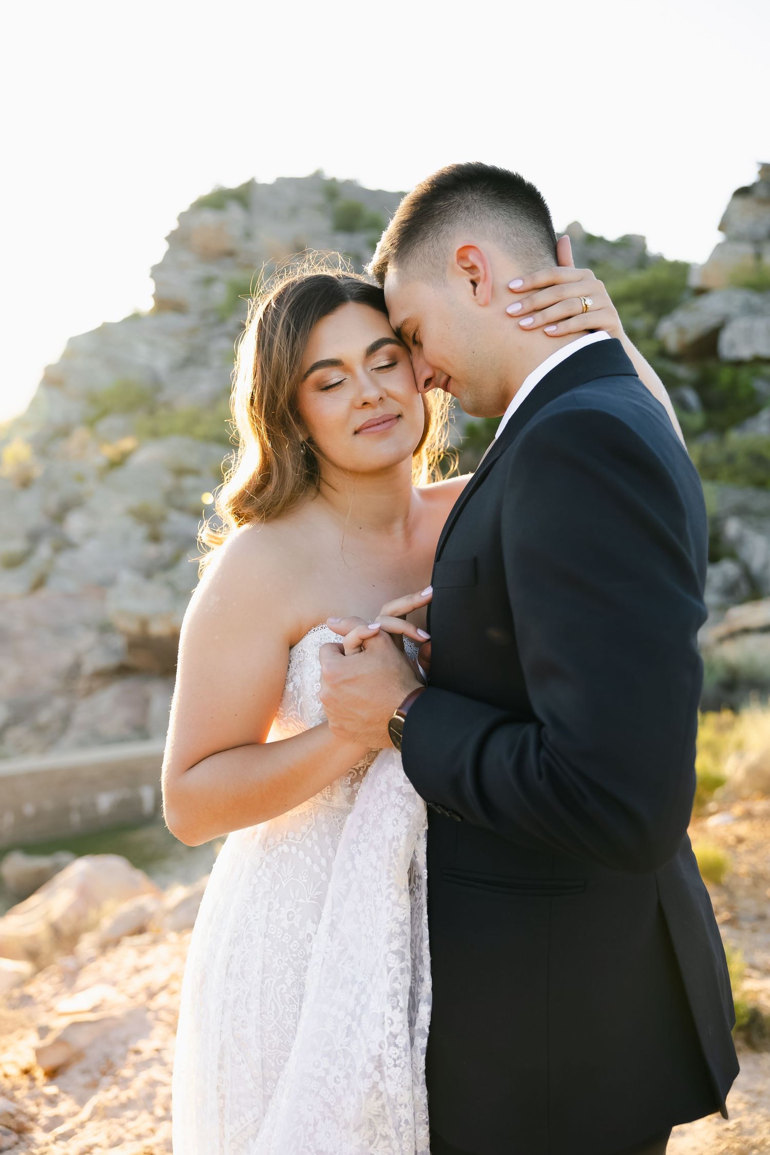 Romantic wedding portraits showing intimate moments between newlyweds against a desert landscape.