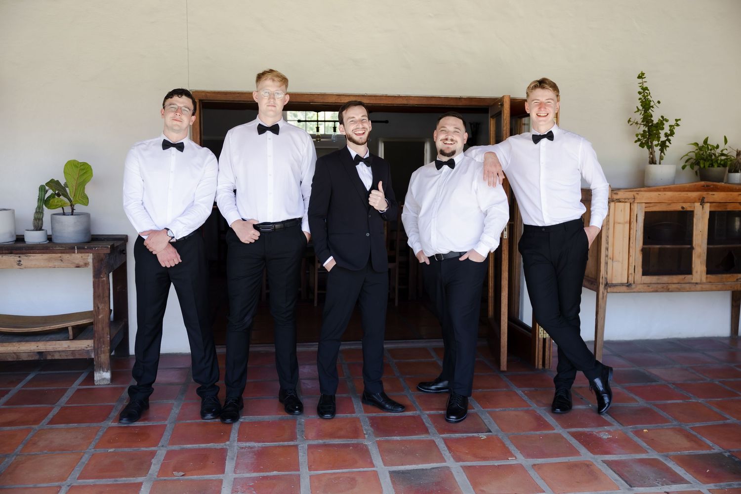 Group of people in formal black and white attire standing in line on terracotta tiles.